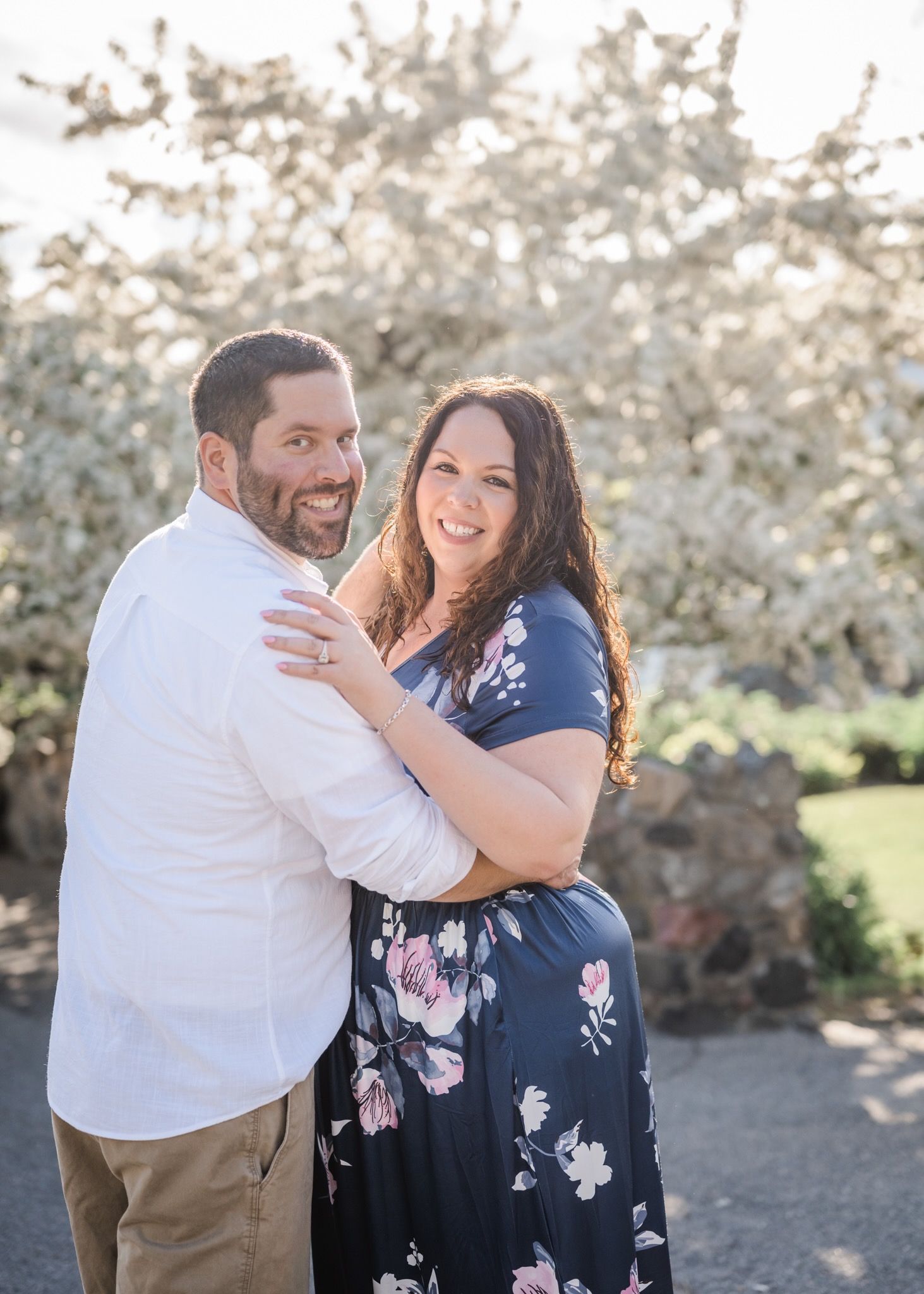 A couple laughs together against a backdrop of blooming cherry trees.