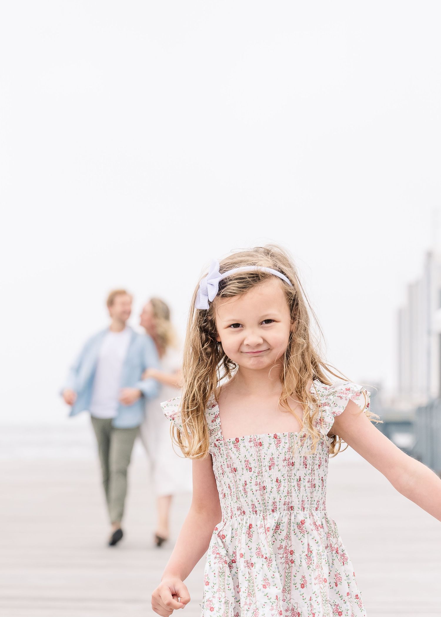 Candid portrait on a pier with people walking in soft focus background.