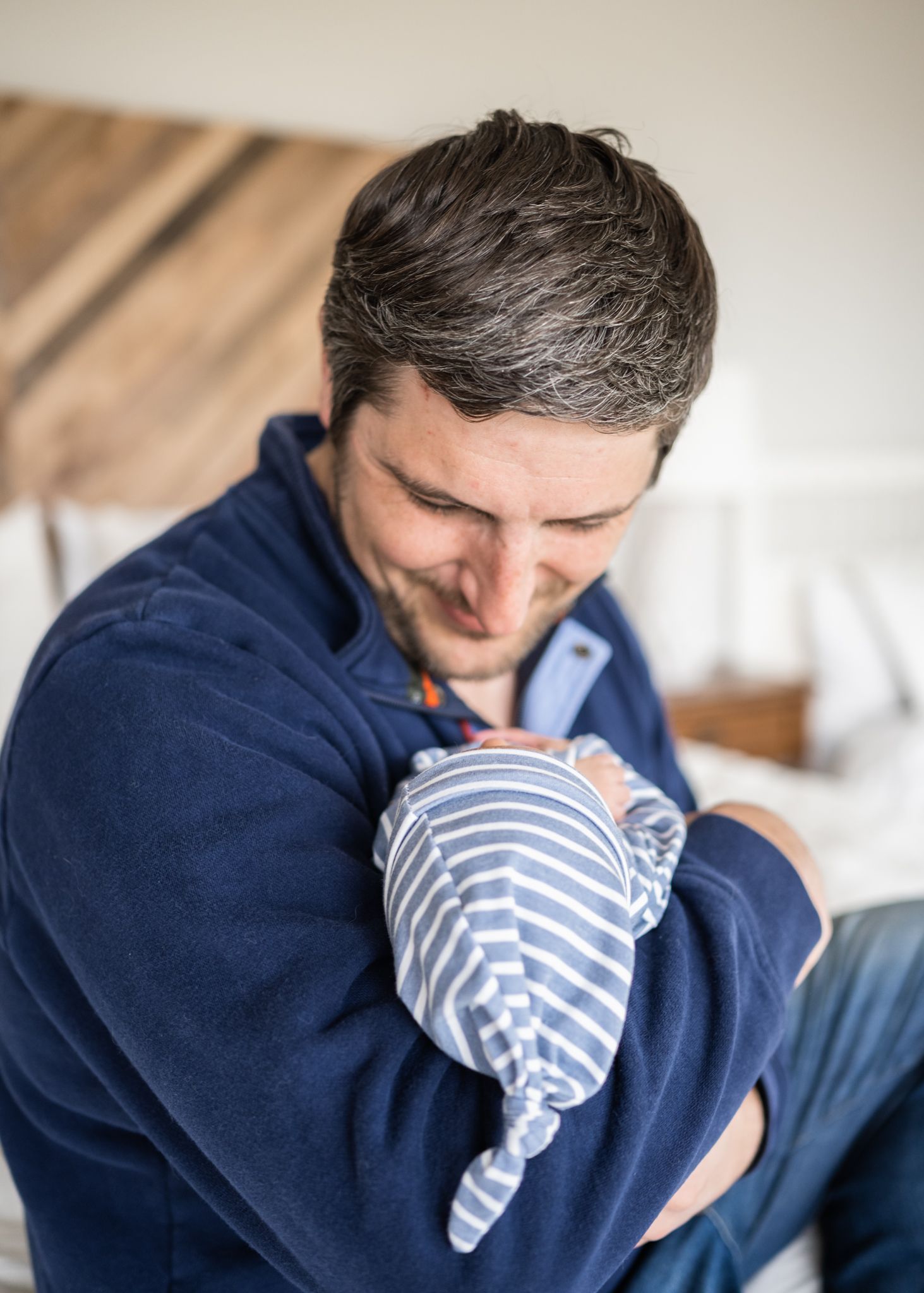 Tender moment between parent and newborn wrapped in striped blanket.
