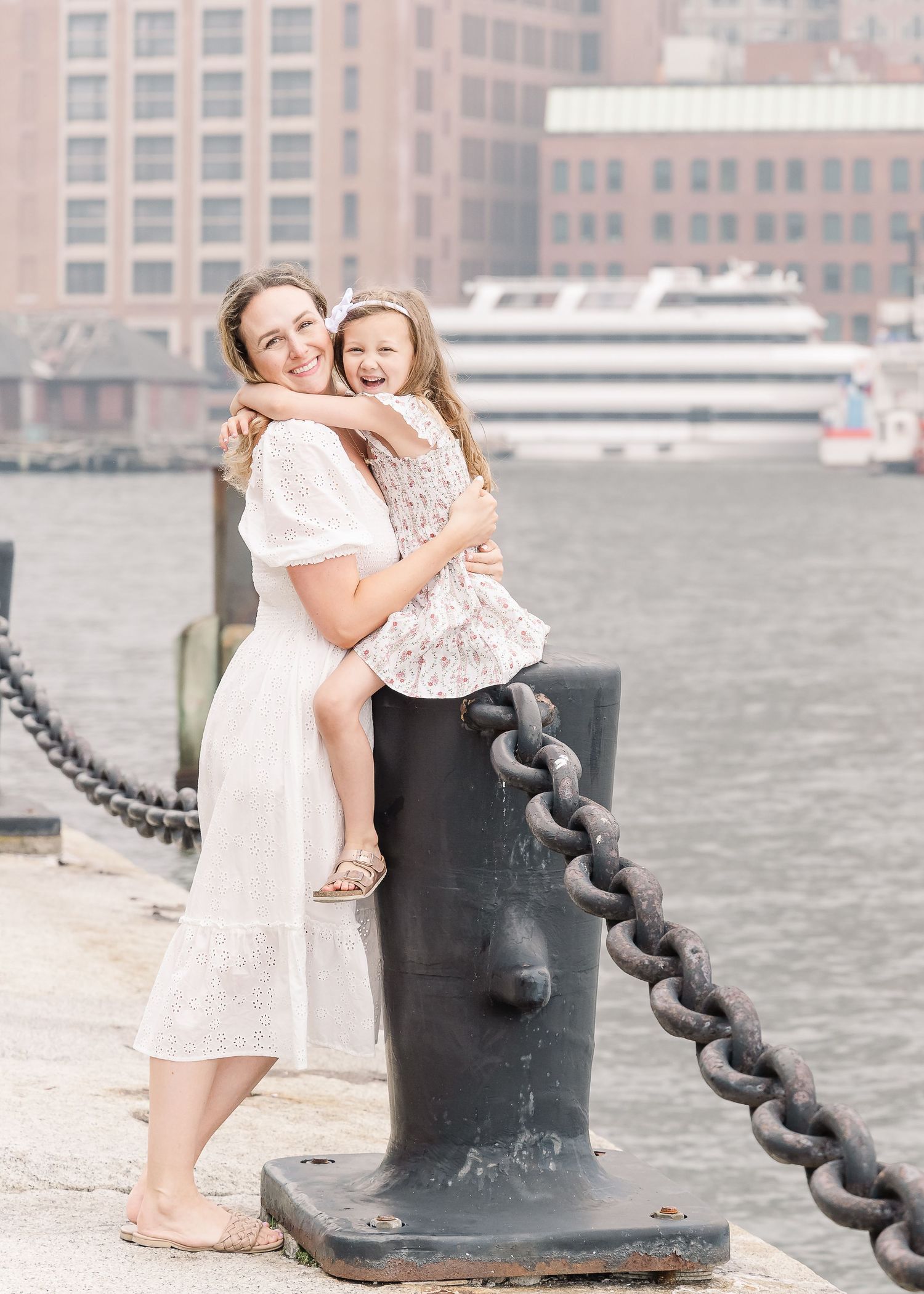Sweet embrace captured on a harbor dock with boats and buildings in the background.