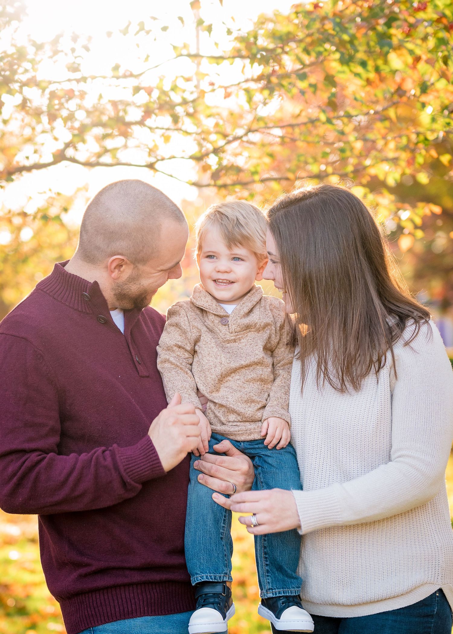 A family shares a loving moment together on a golden autumn afternoon in the park.
