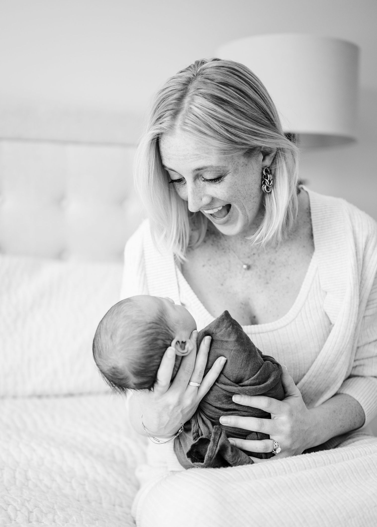 Tender moment between parent and baby on white couch.