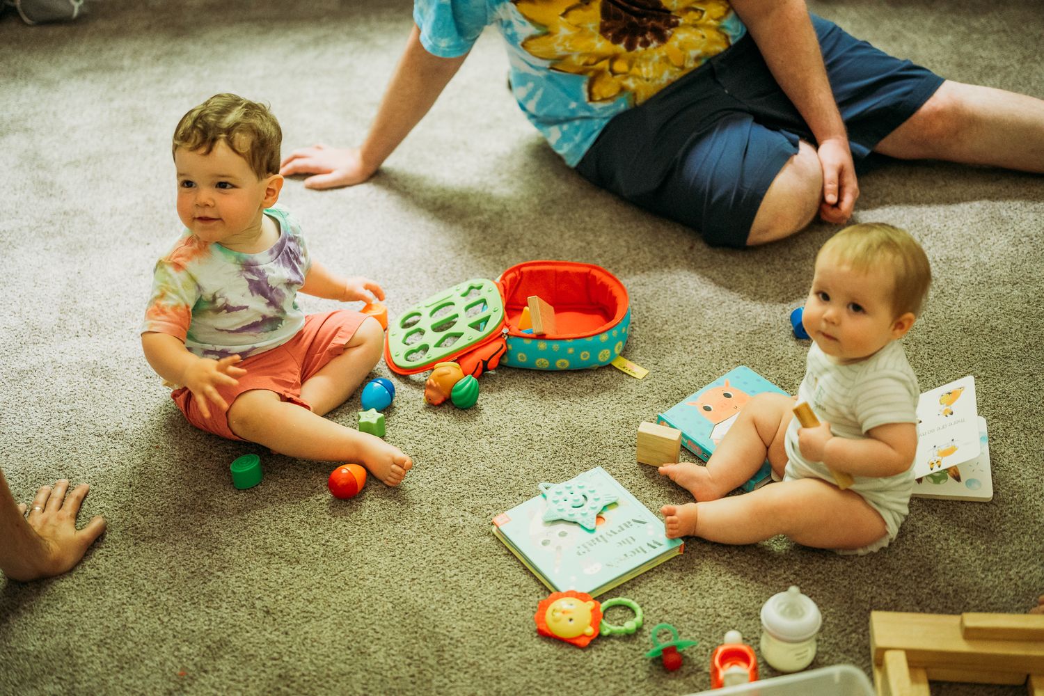 Children playing with colorful toys on carpet during playtime.