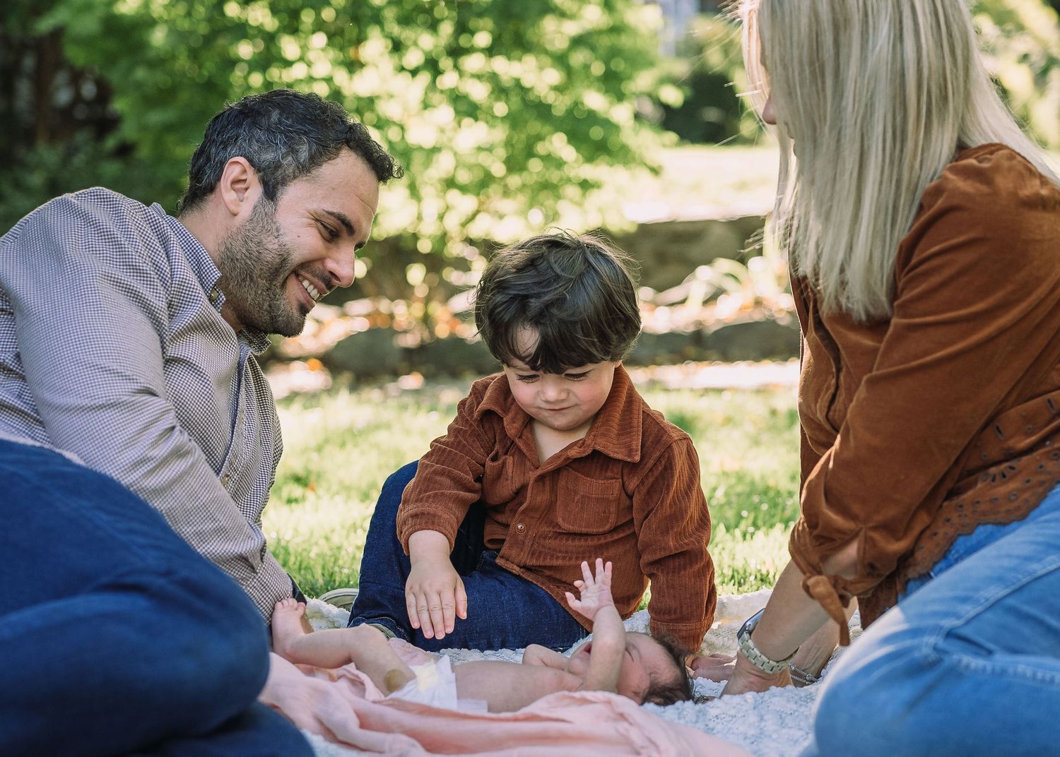 Family enjoying outdoor picnic together on blanket in sunny garden.