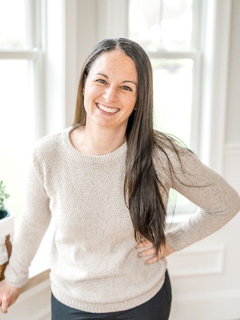 Casual indoor photoshoot featuring warm cream sweater against bright white interior.
