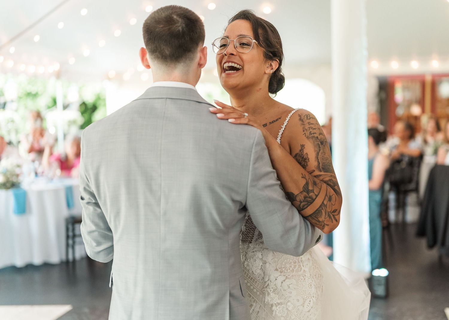 Dancing couple enjoying a romantic moment at their wedding reception with candid laughter and movement.