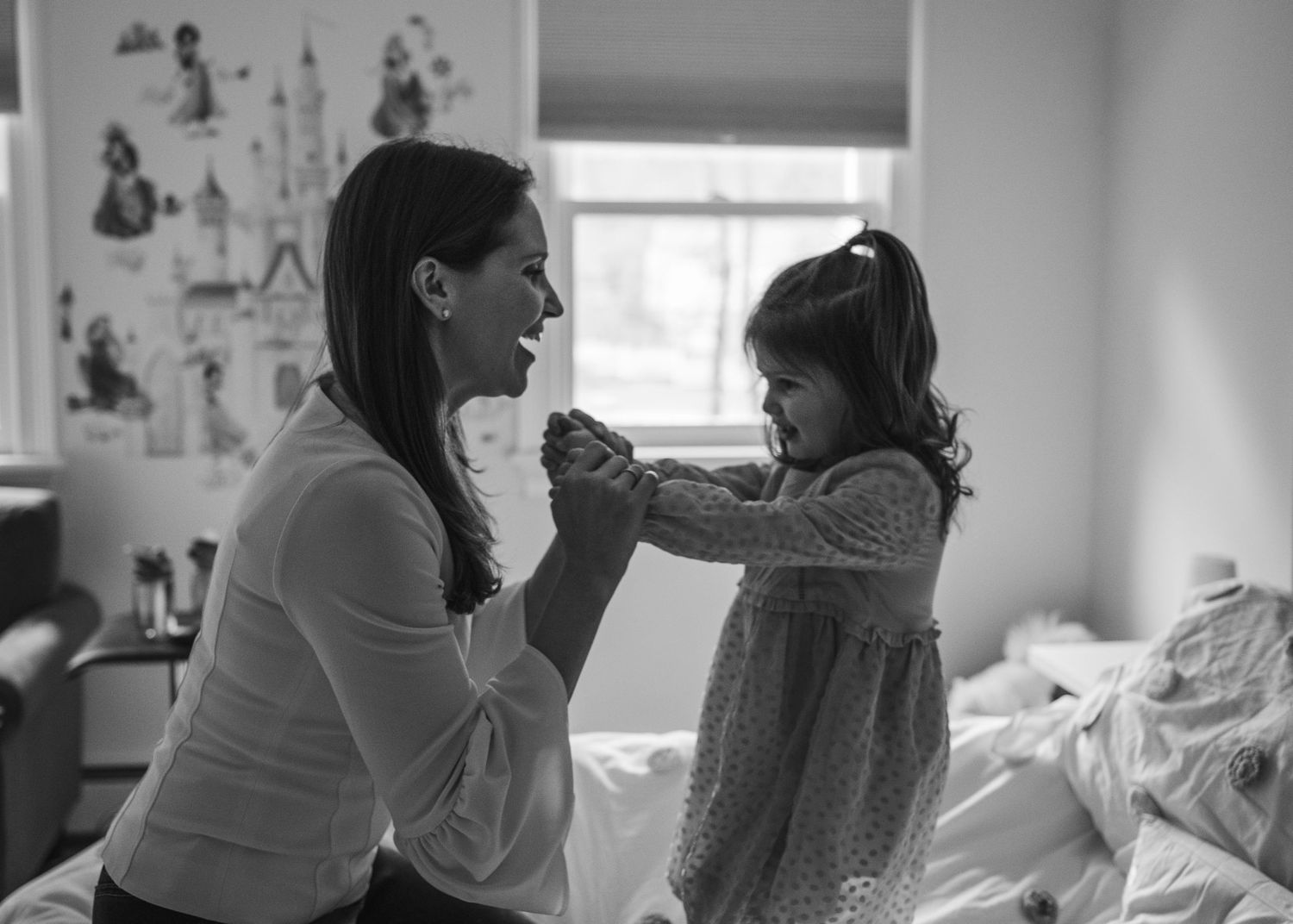 A tender moment shared between parent and child playing together in a soft black and white indoor setting.