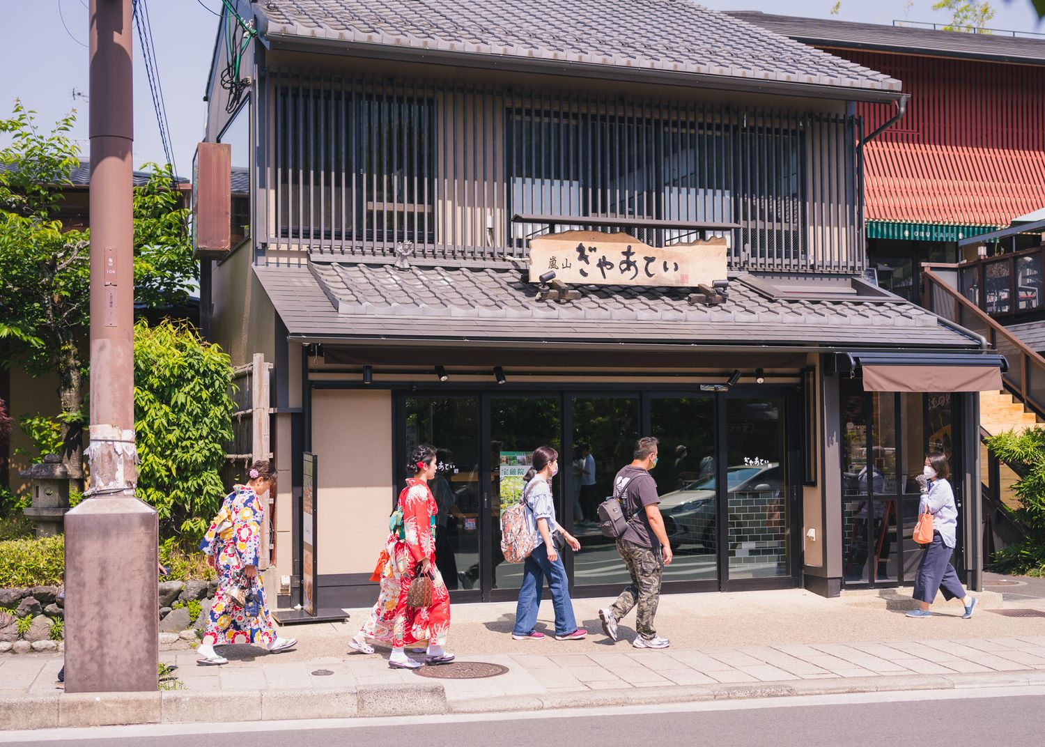 Traditional Japanese storefront with wooden facade and people walking on street in Kyoto.