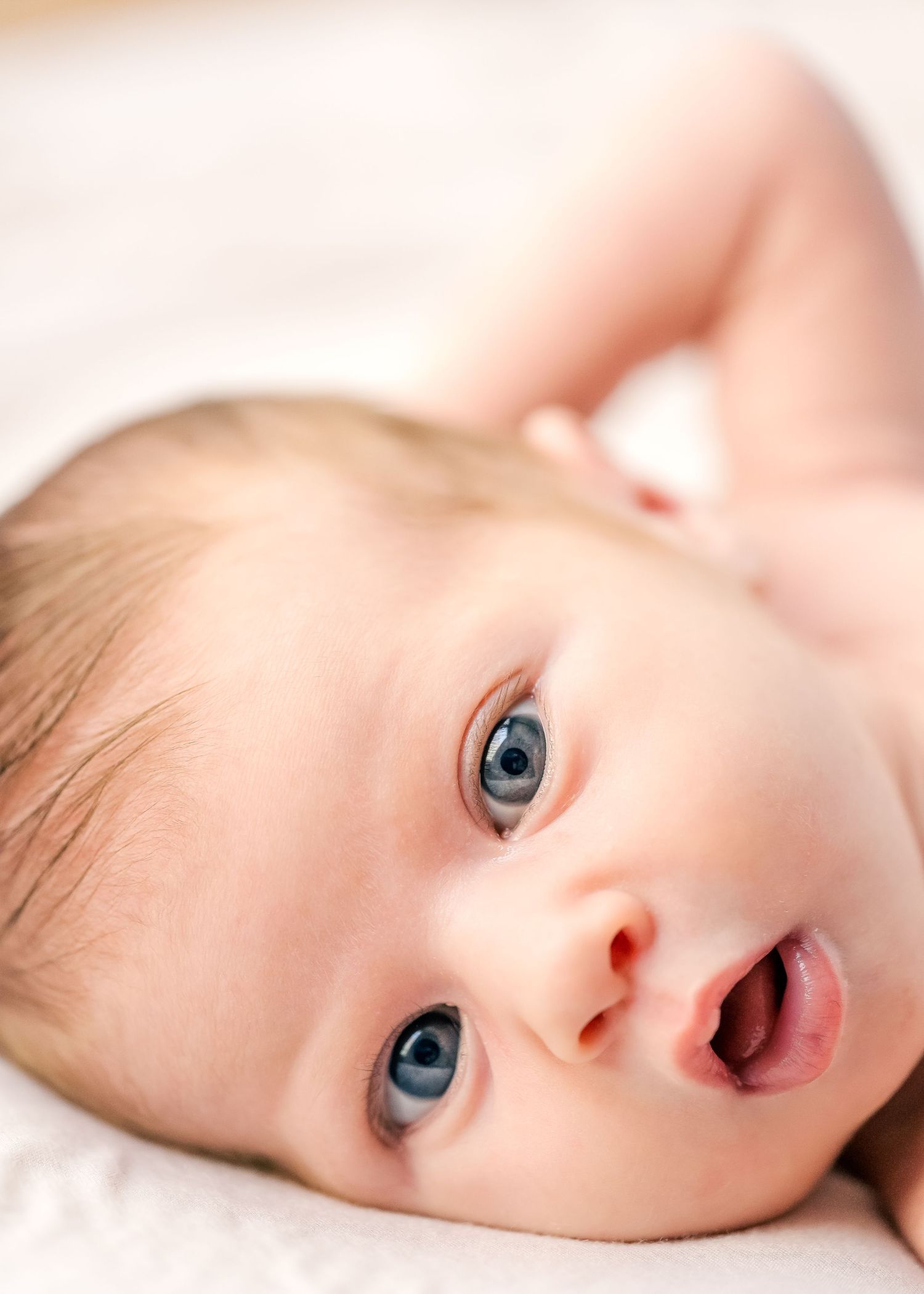 Sweet close-up portrait of infant with bright blue eyes and rosy cheeks.