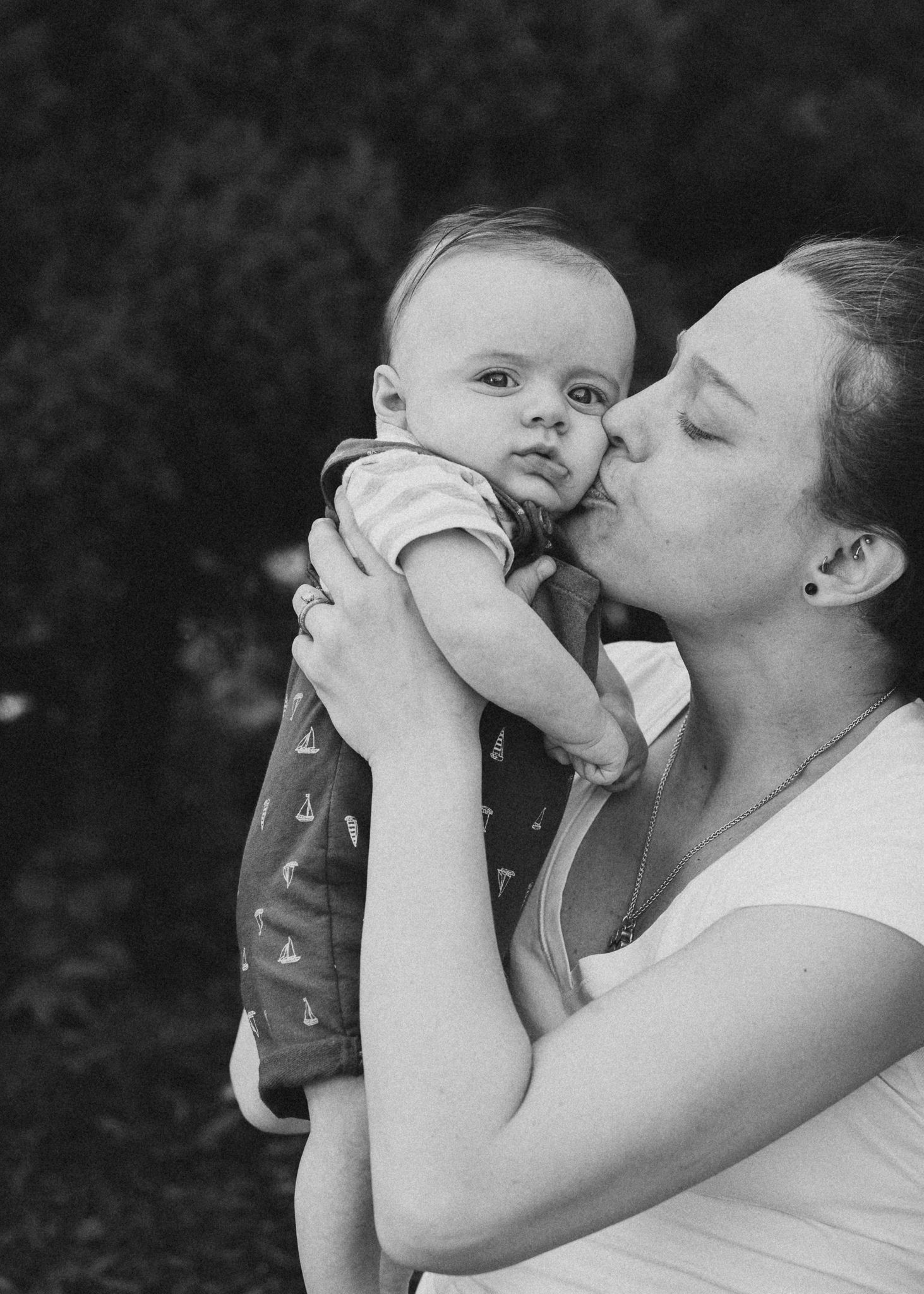 Black and white intimate portrait showing tender moment between parent and baby.