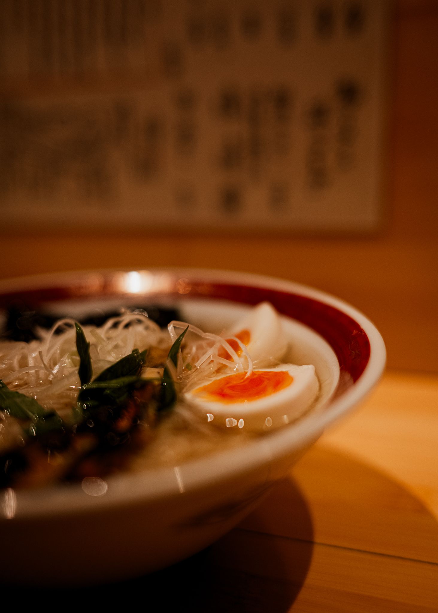 A steaming bowl of ramen with noodles, soft-boiled egg, and seaweed in a rich broth.