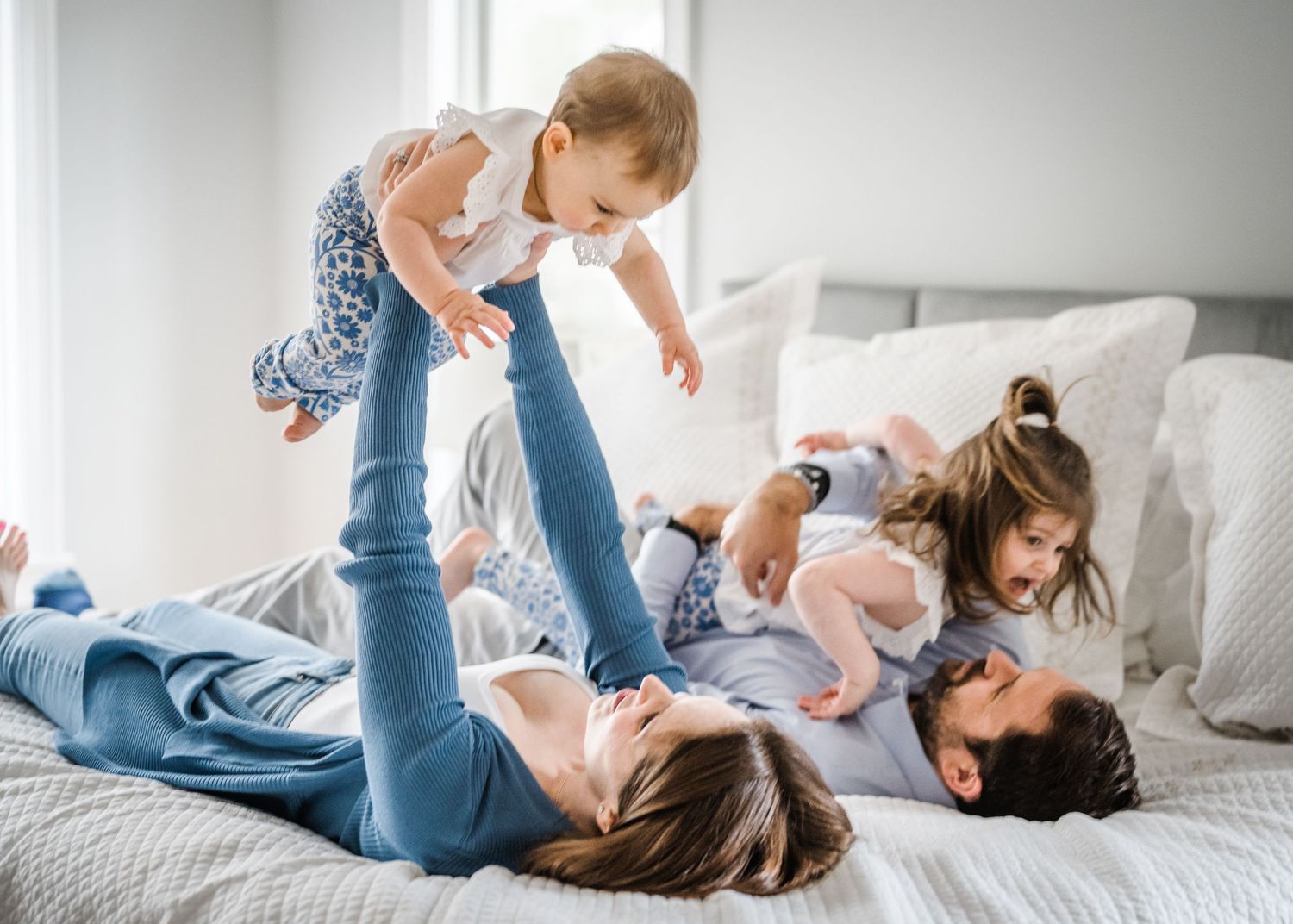 Family having fun playing together on bed in bright bedroom.