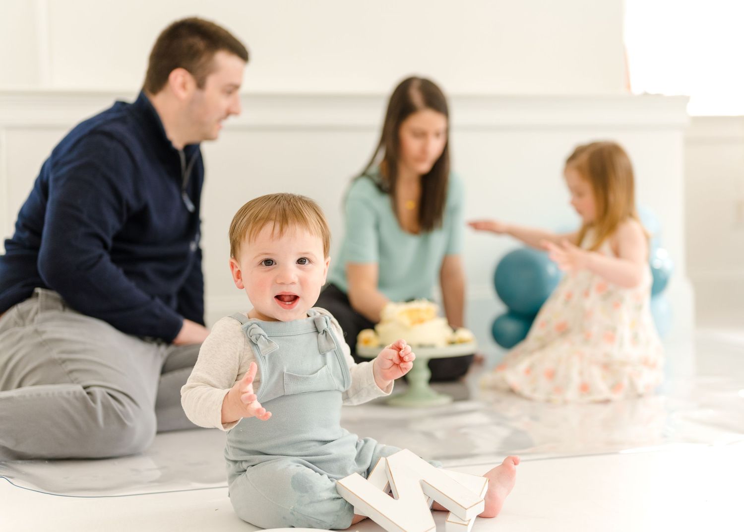 Family gathering in a bright room with adults and children sitting on the floor during a celebration.