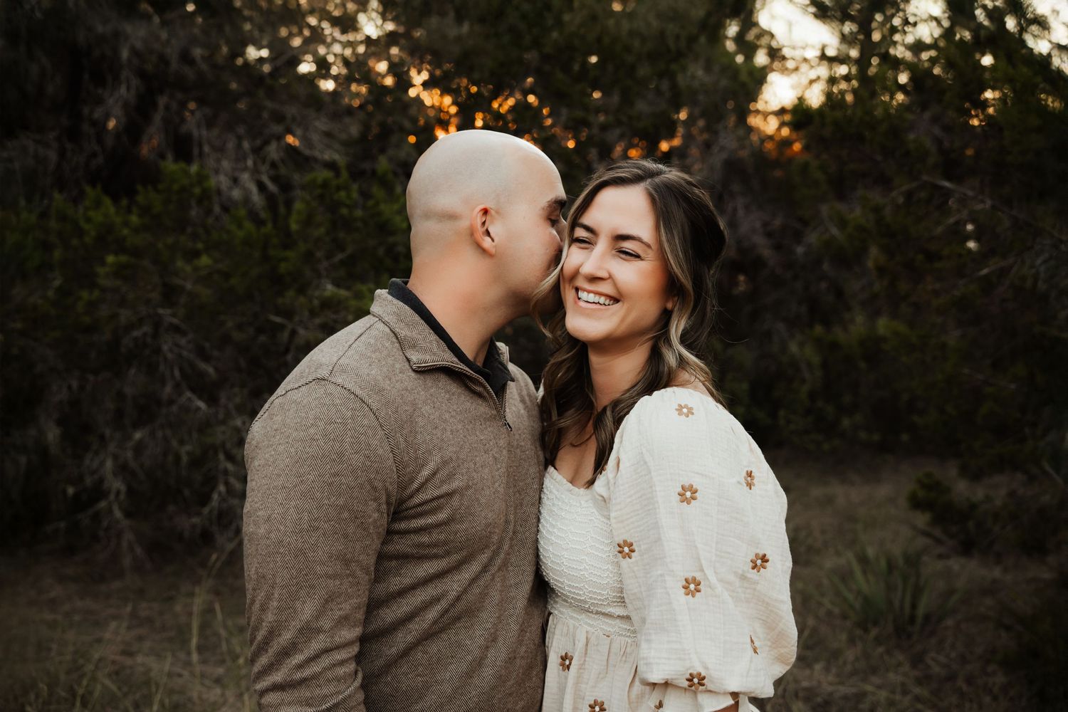 Man whispering in smiling womans ear during romantic outdoor golden hour portrait.