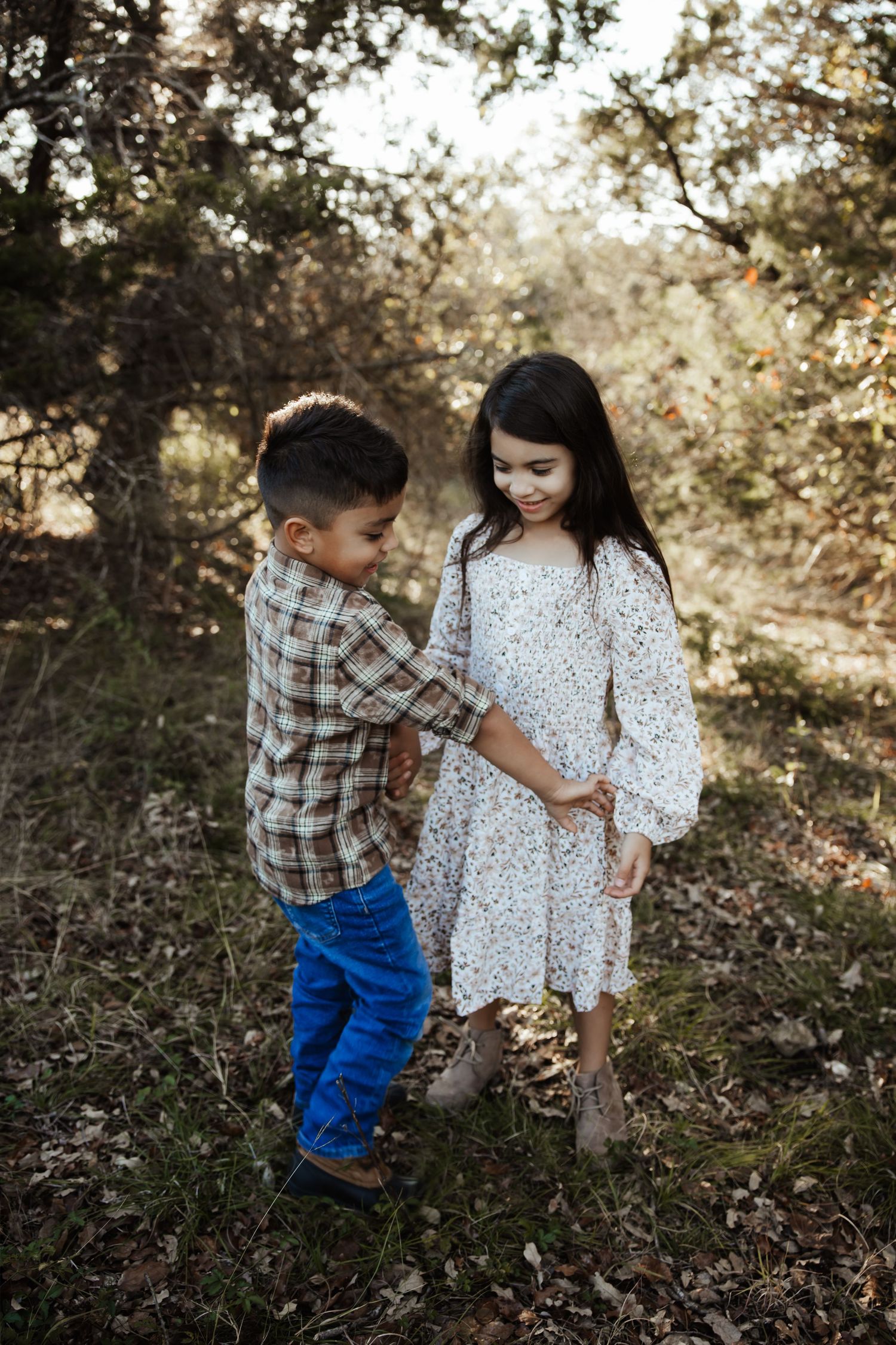 Young boy and girl holding hands and playing together in a forest setting.