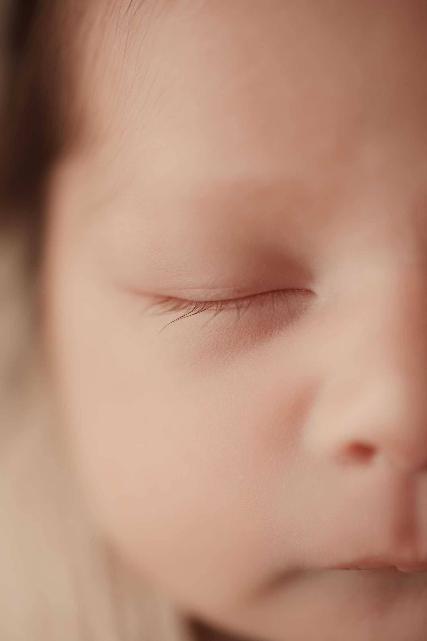 Extreme close-up of a sleeping newborns delicate eyelashes and soft skin.