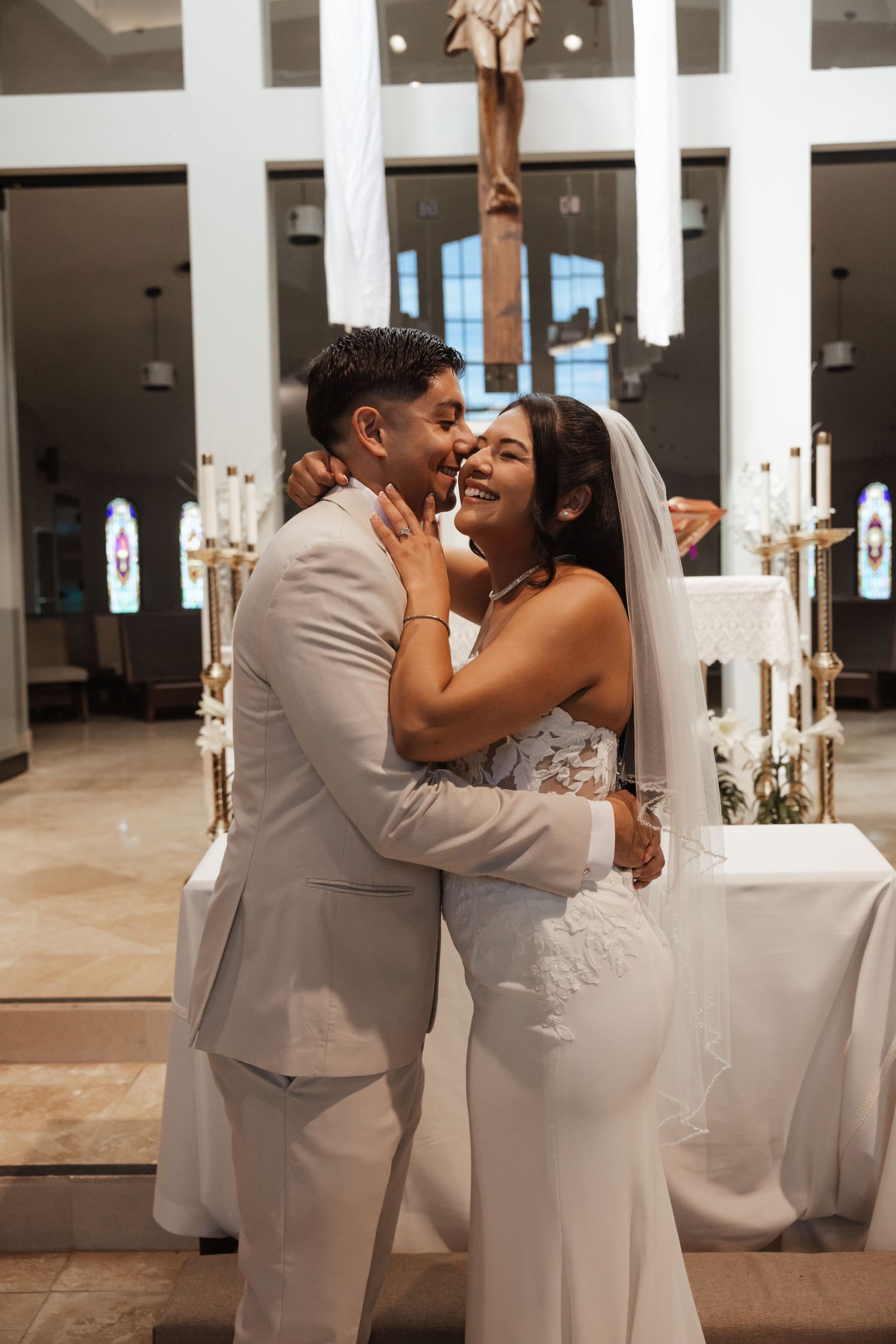 A joyful bride and groom share a romantic embrace at the altar during their church wedding ceremony.