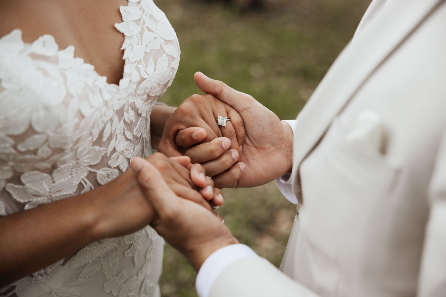 Close-up of bride and groom exchanging wedding rings during ceremony, bride in lace dress.