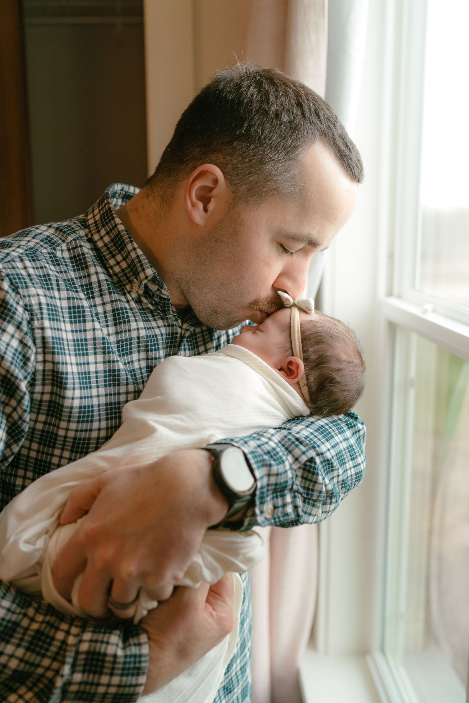 A man is tenderly holding and cradling a newborn baby in his arms.