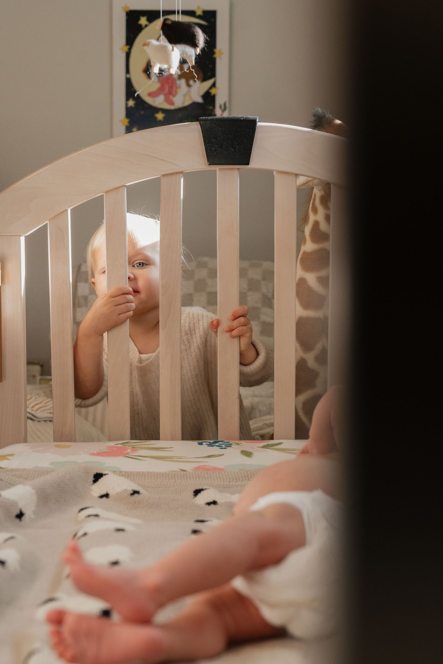 A baby lying in a crib surrounded by stuffed animals and a mobile hanging above.