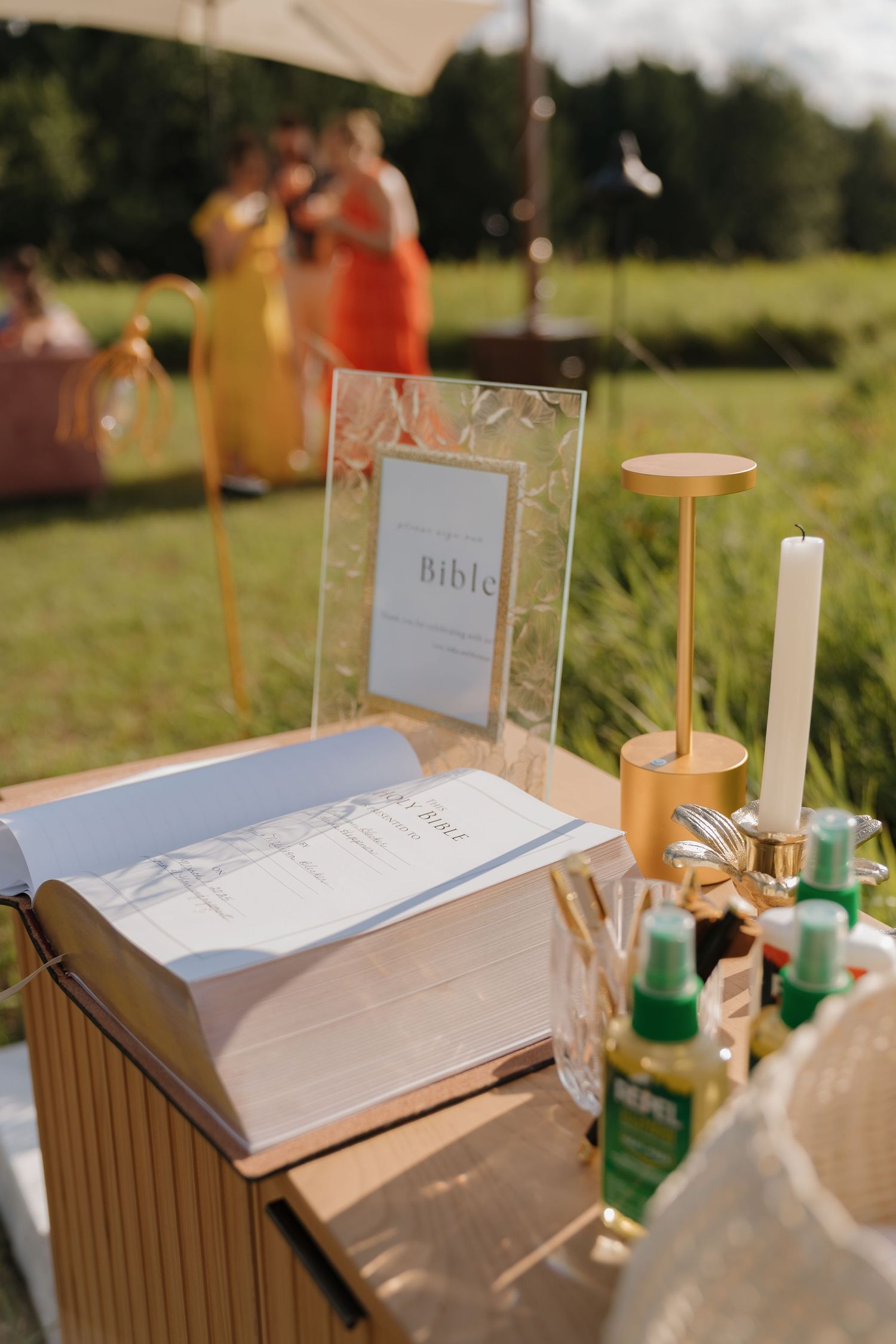 An outdoor scene with a Bible on a wooden box, surrounded by candles and other religious items.