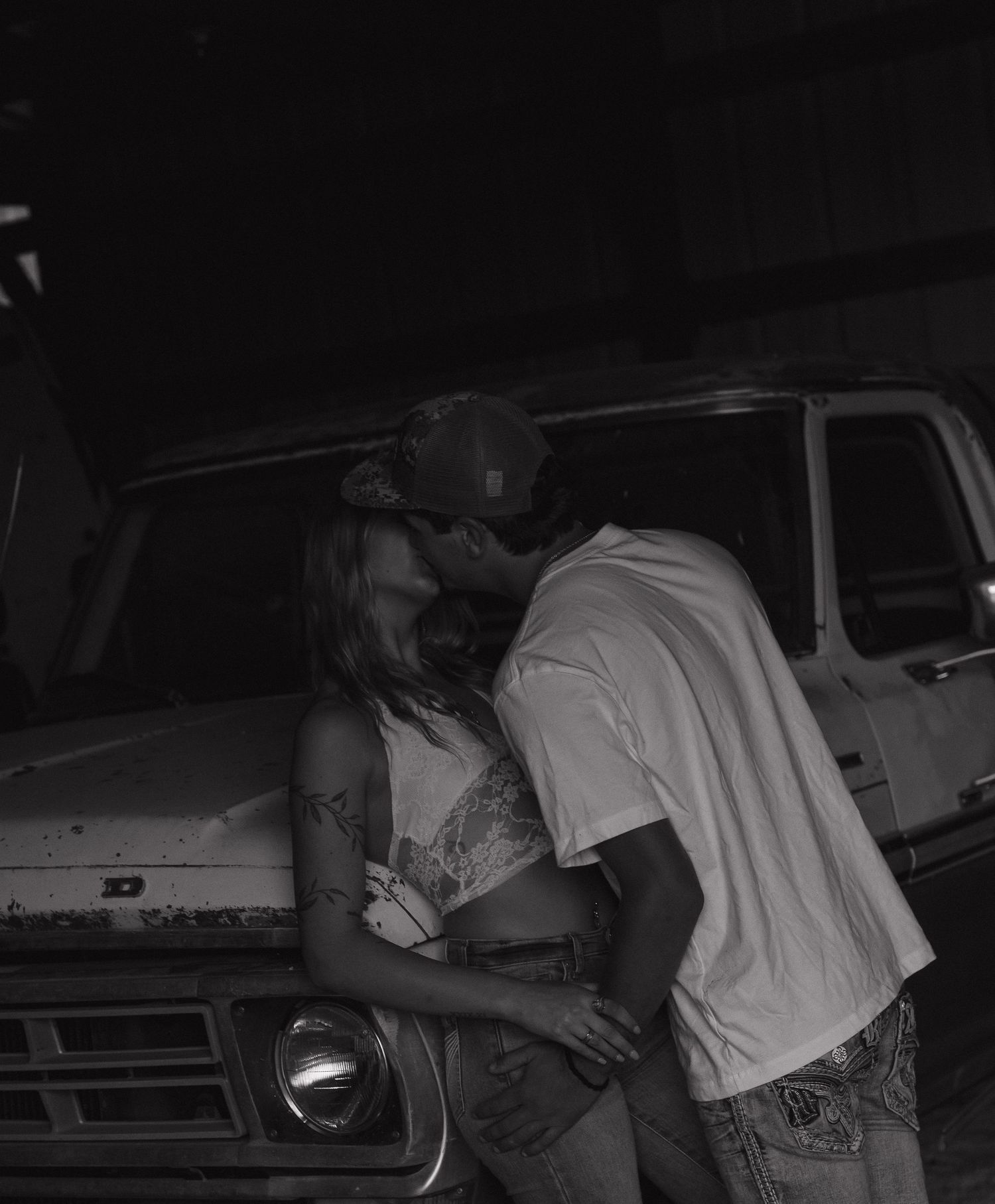 The image shows two people embracing in a dimly lit environment, possibly a vehicle.