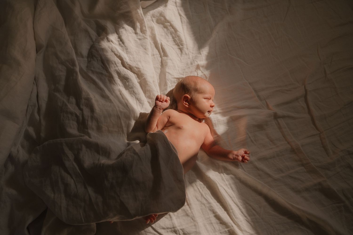A newborn baby is swaddled in a soft blanket, resting peacefully on a bed.