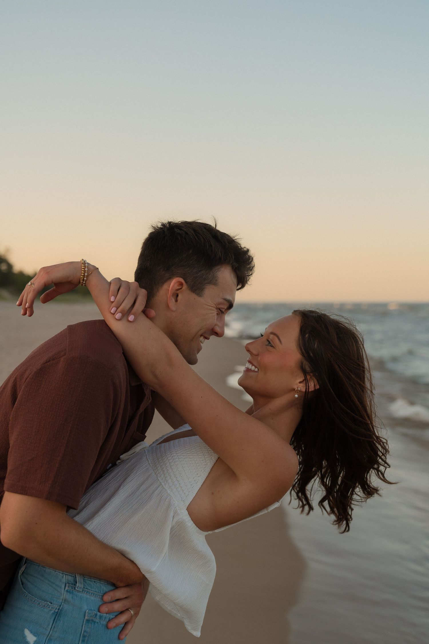A couple embracing and gazing at each other on a beach at sunset.
