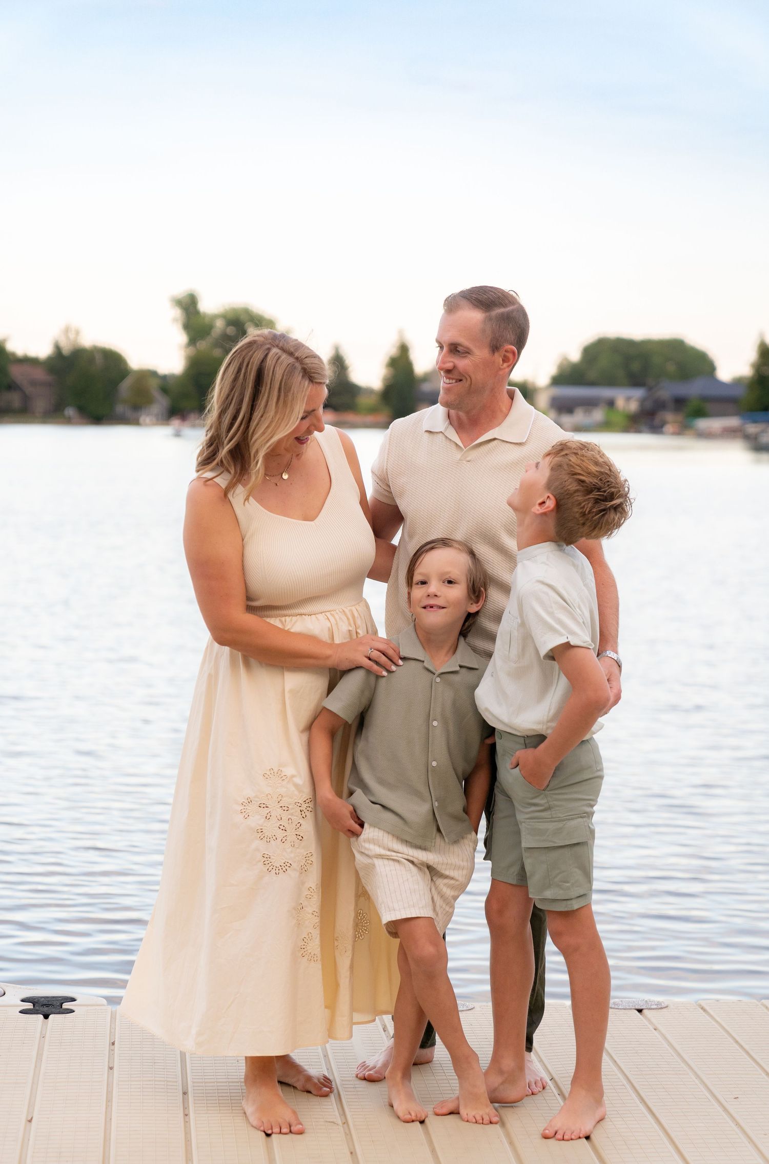 A happy family of four standing on a wooden dock near a body of water.