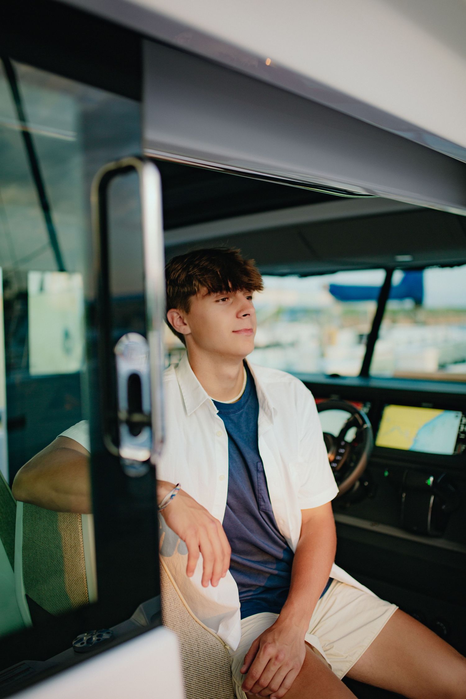 A young man sits in the front seat of a vehicle, looking thoughtful.