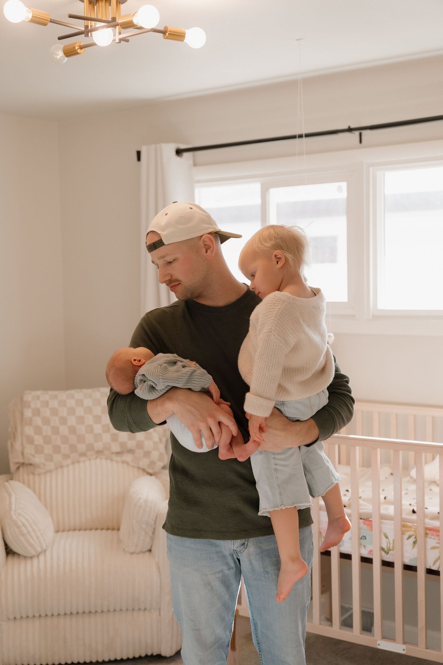 A man holding a young child in a cozy nursery room with a crib and other furnishings.