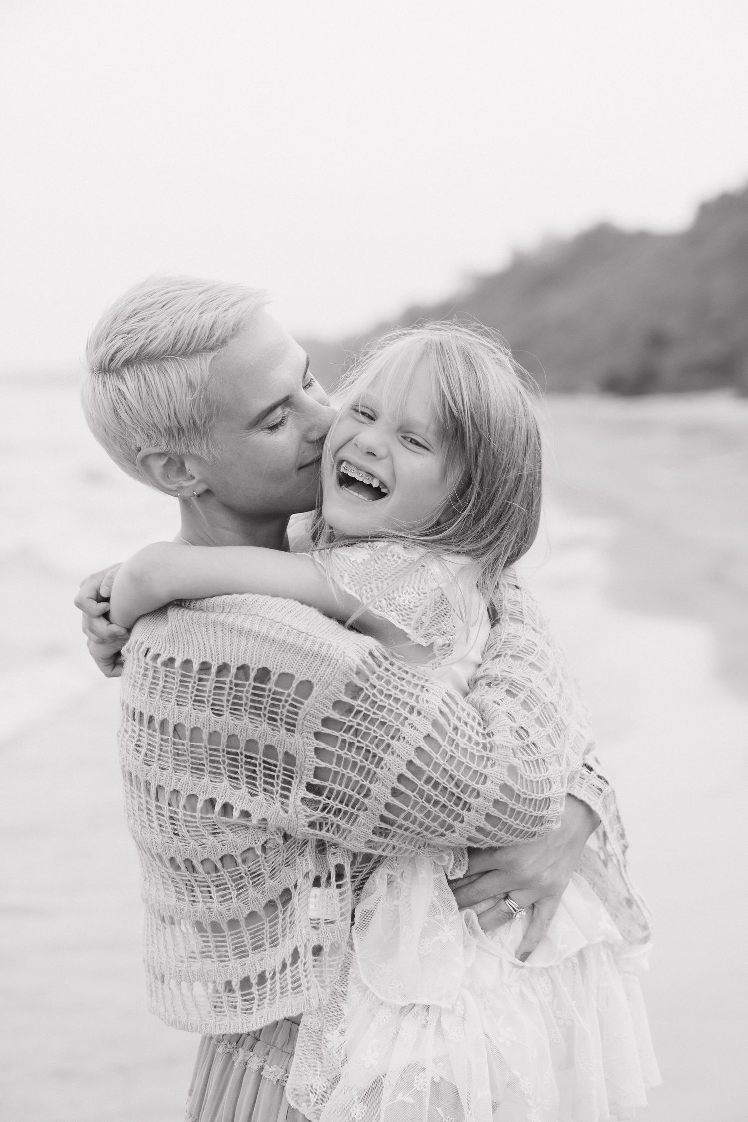 Embracing and smiling affectionately on a beach.