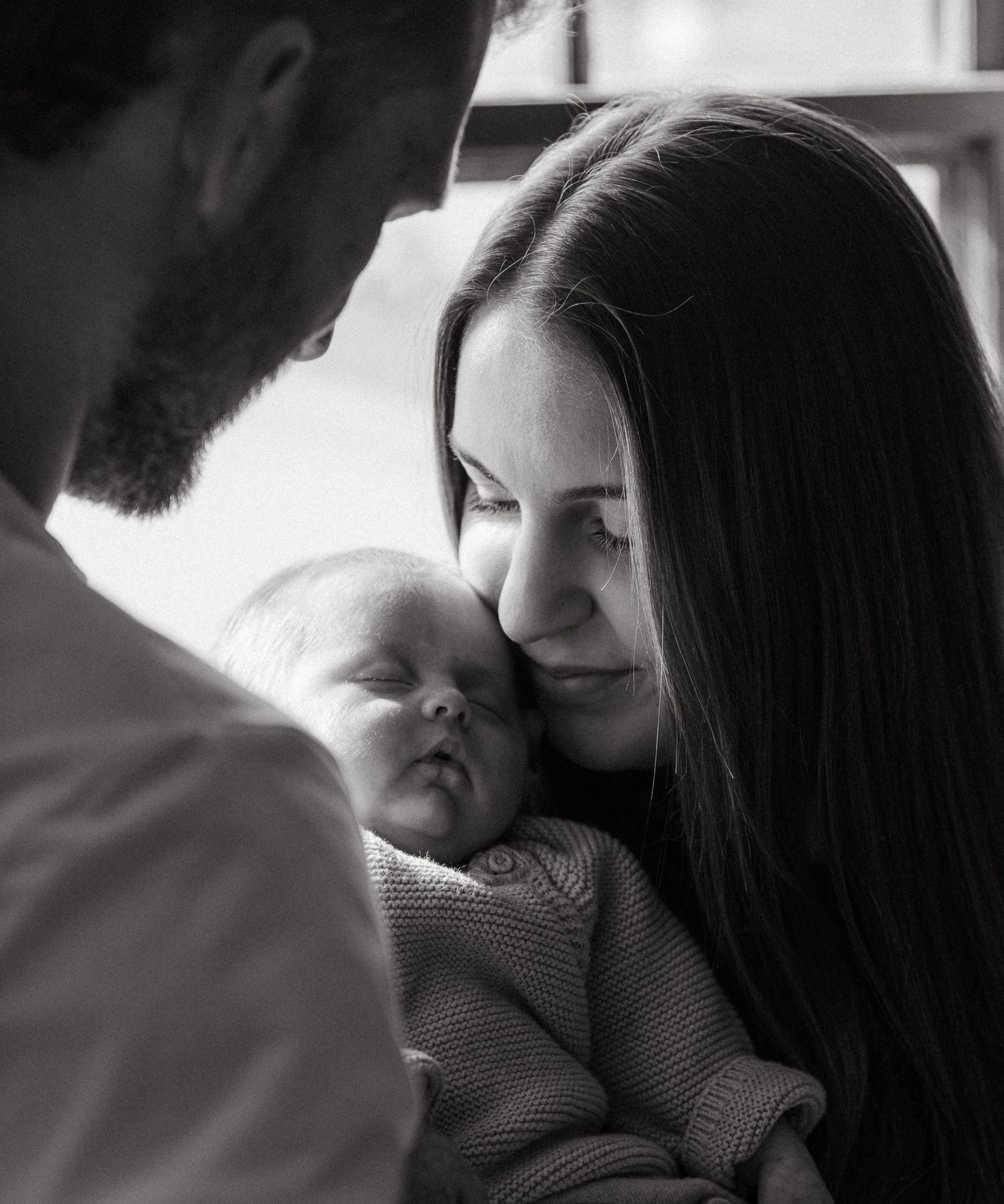 A black and white image shows a woman tenderly holding a sleeping baby in her arms.