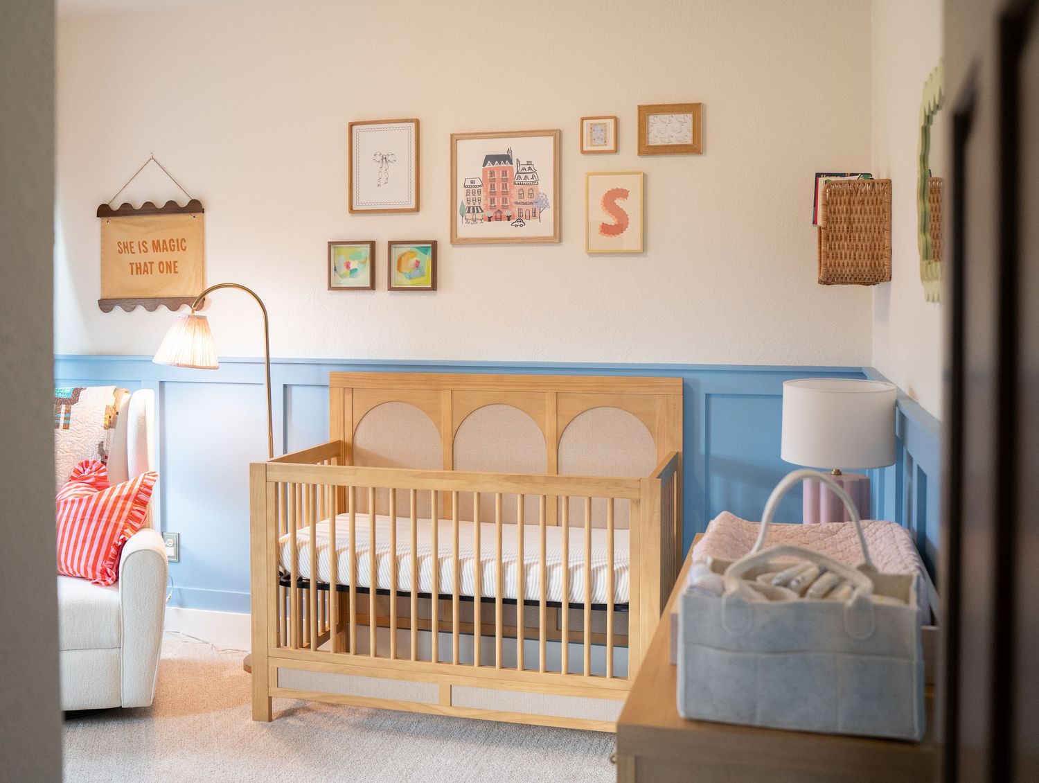 A cozy nursery with a wooden crib, framed artwork, and a plush armchair, creating a warm and inviting space.