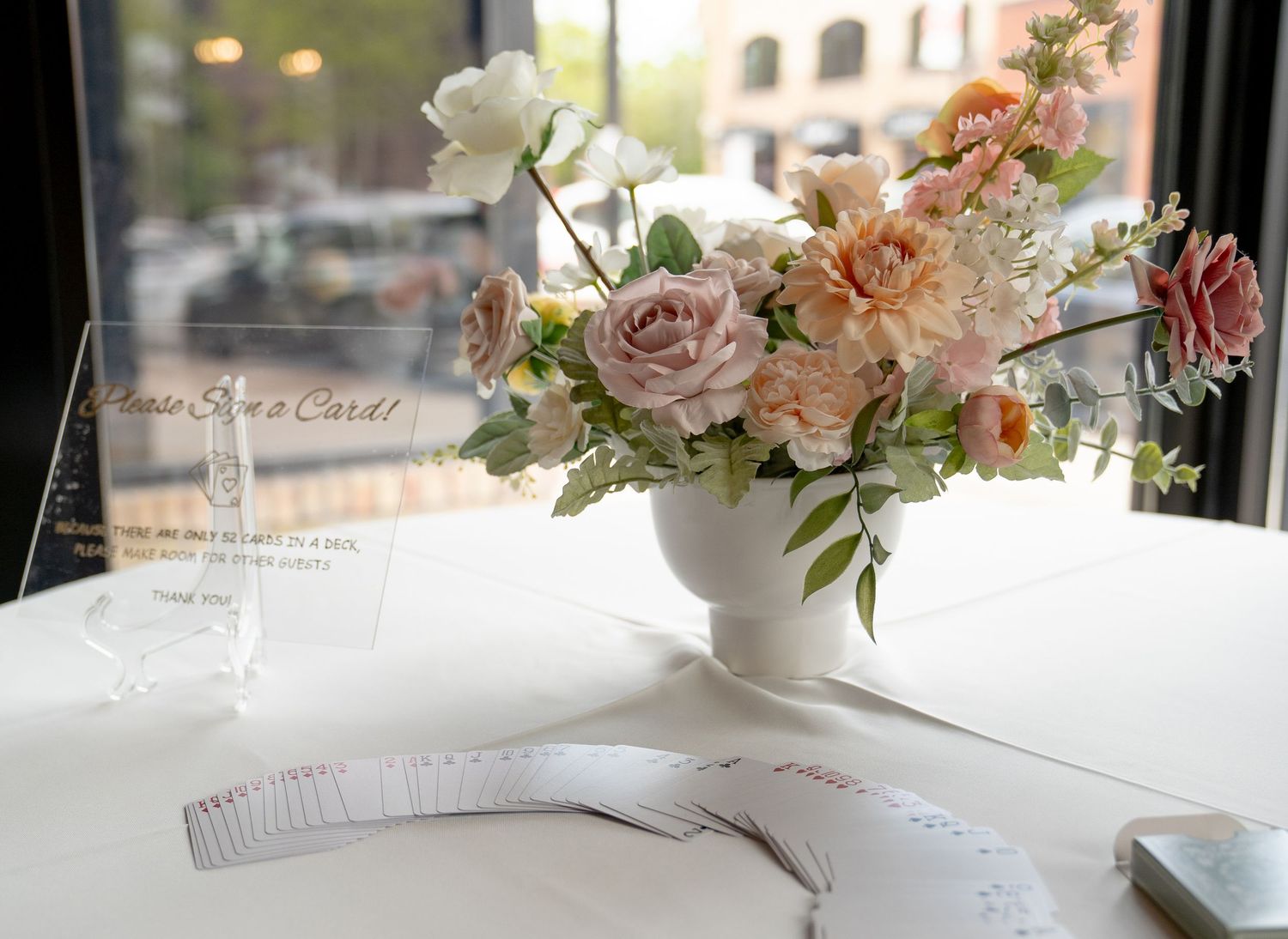 A bouquet of delicate white and pink flowers arranged in a vase on a table by a window.