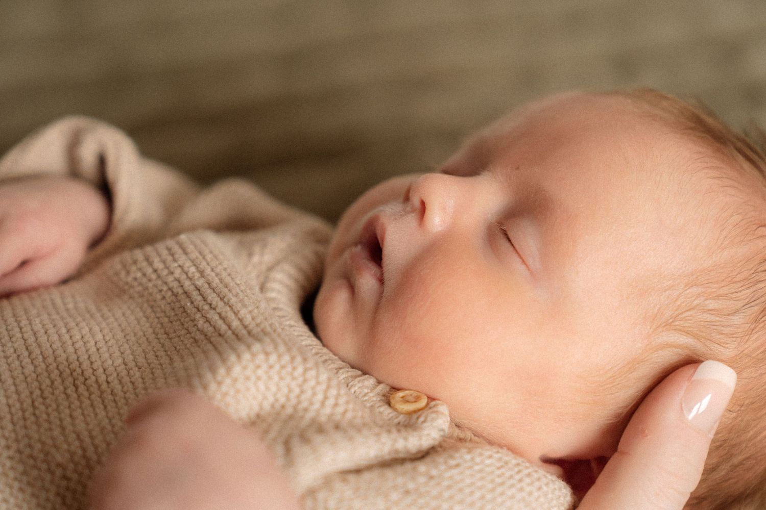 A newborn baby sleeps peacefully, wrapped in a cozy blanket.