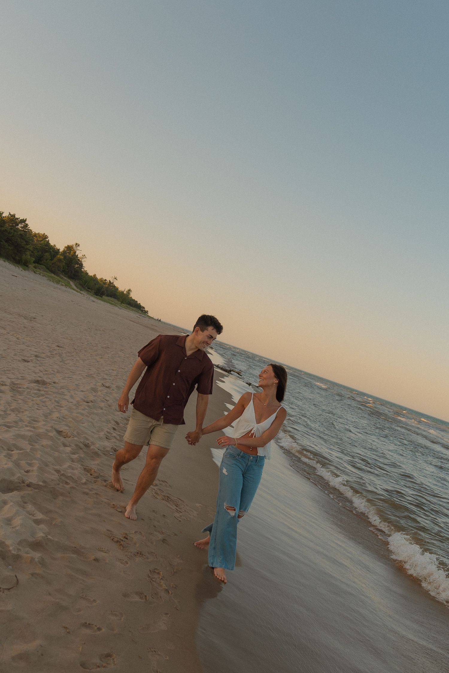 Two people walking together along a sandy beach at sunset.