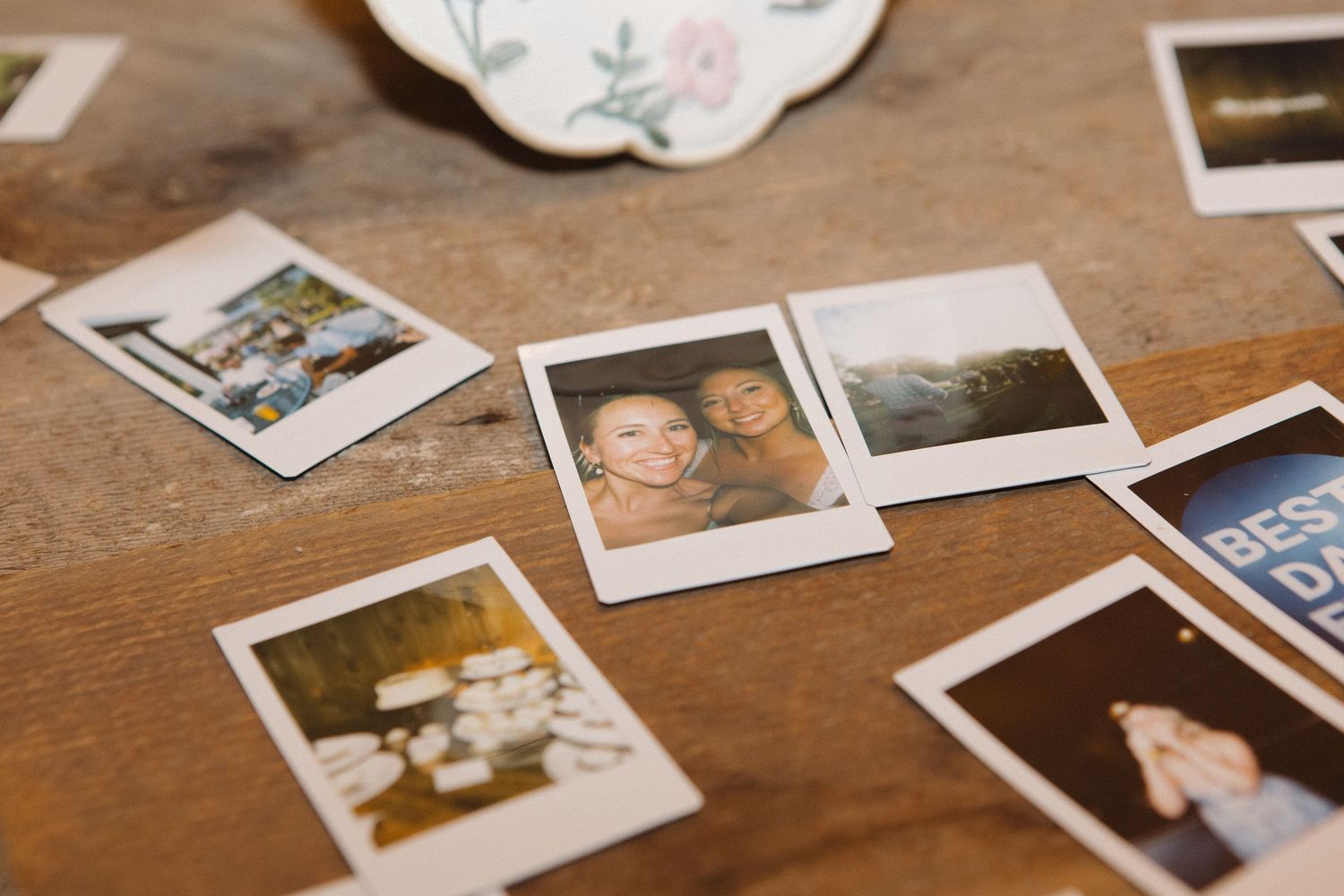 A collection of vintage-style polaroid photographs scattered on a wooden surface.