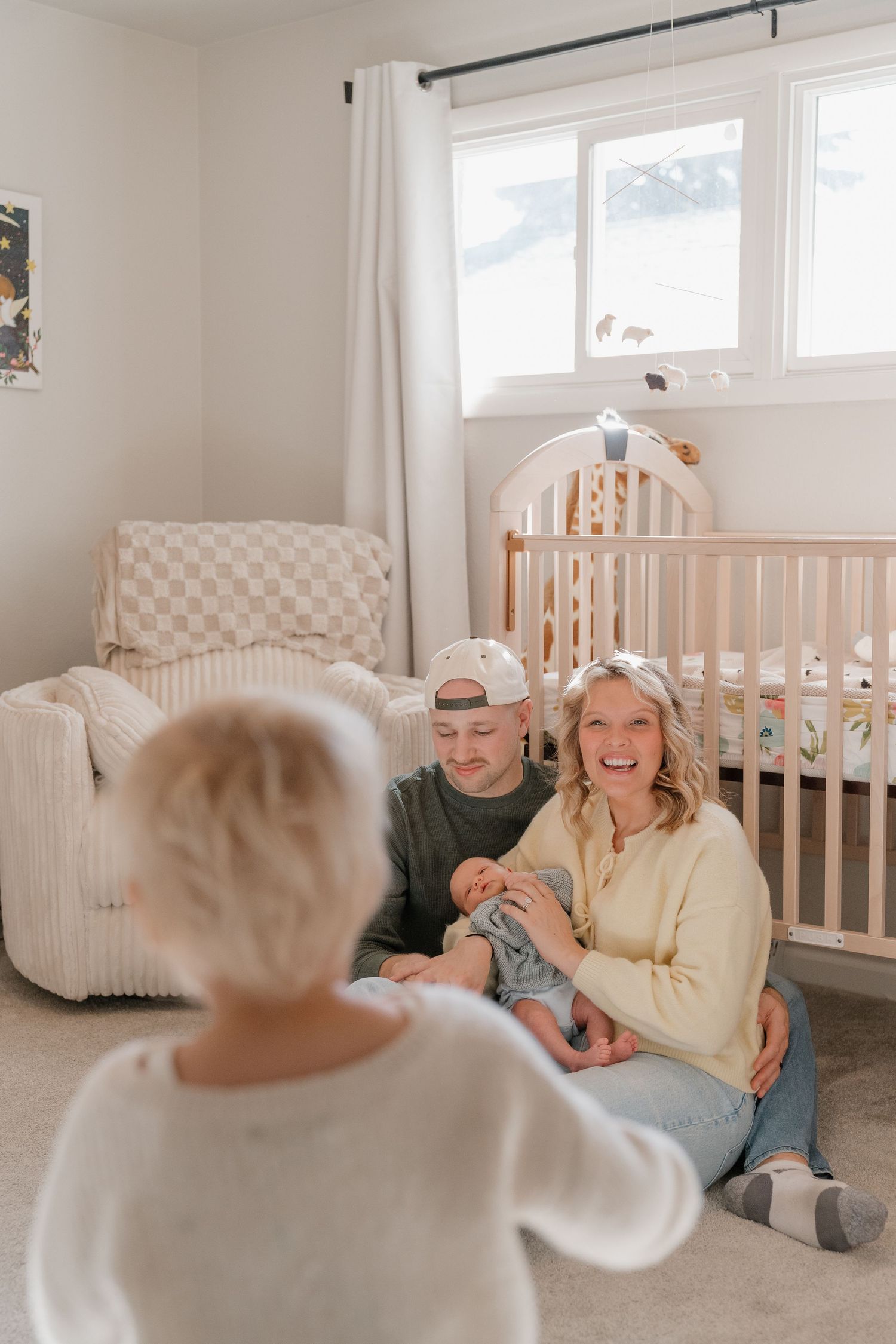A happy family with a young child in a cozy nursery room with a crib and rocking chair.