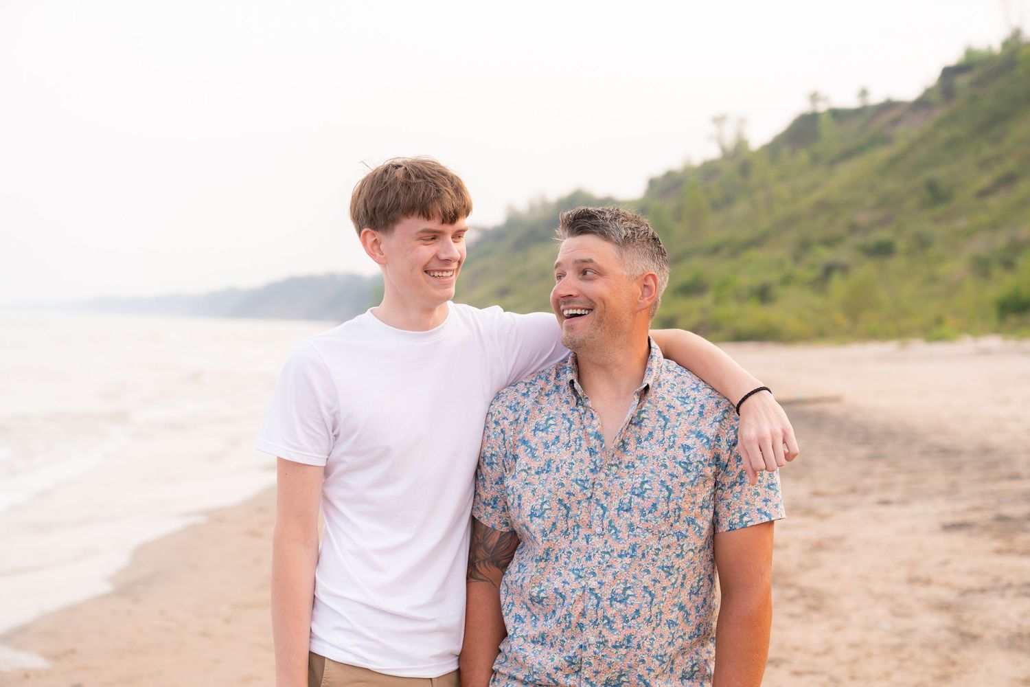 Two people, a younger man and an older man, walking together on a beach.