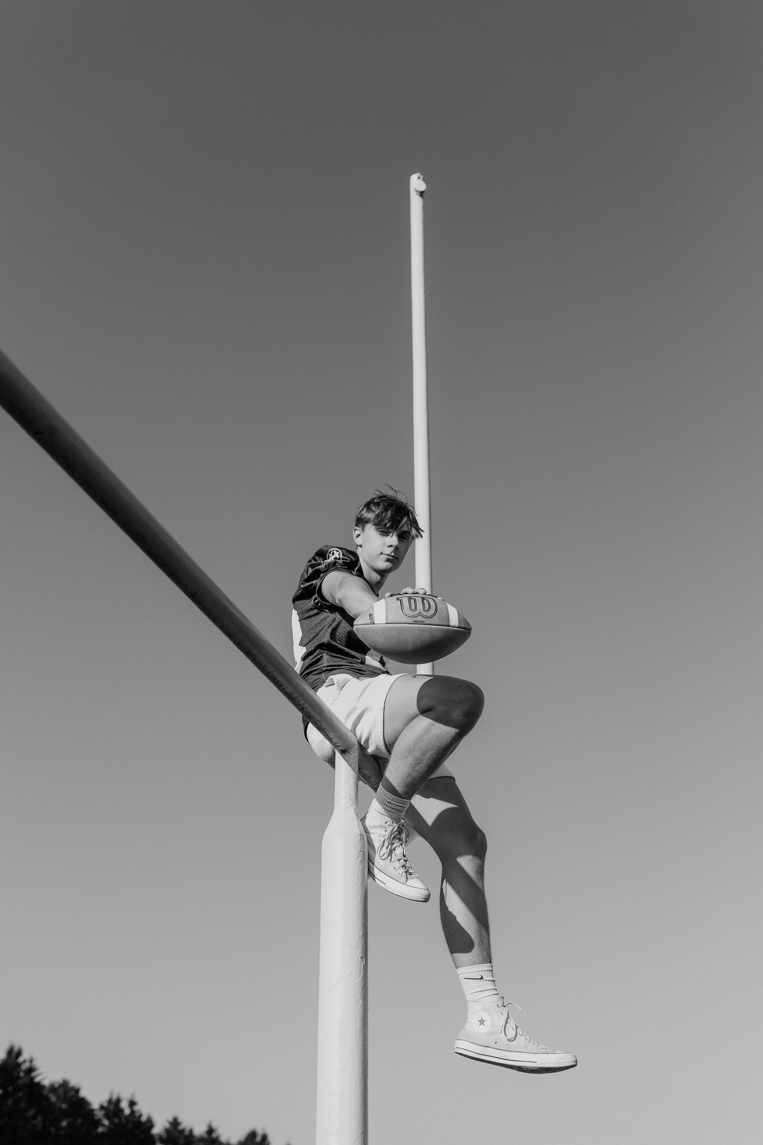 A person is climbing a tall pole against a clear sky background.