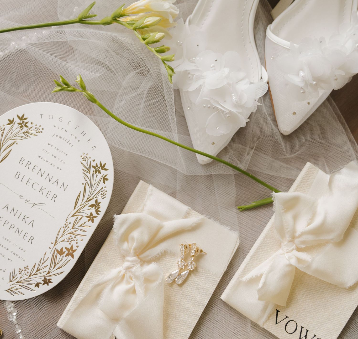 A collection of wedding stationery items including an invitation card, envelope, and a white rose stem.