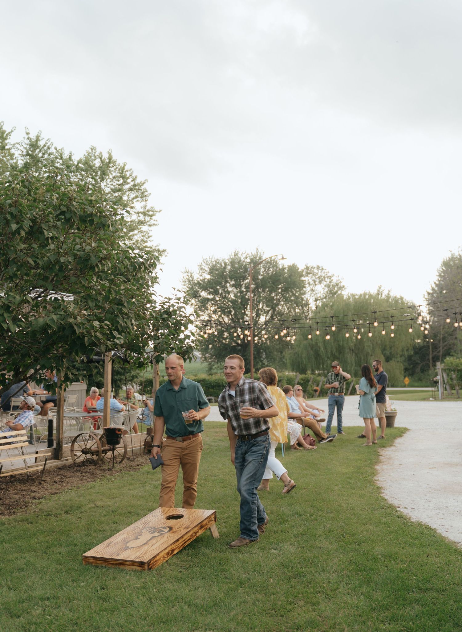 The image shows a group of people gathered in a park, with trees and greenery in the background.