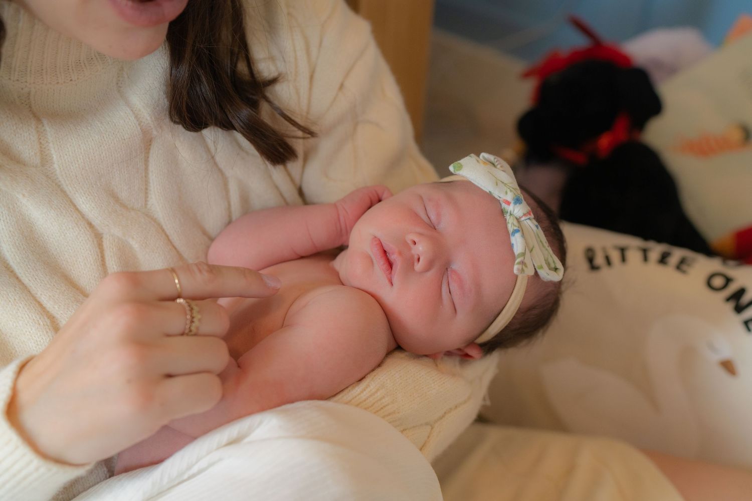 A woman holding a sleeping newborn baby in a white blanket.