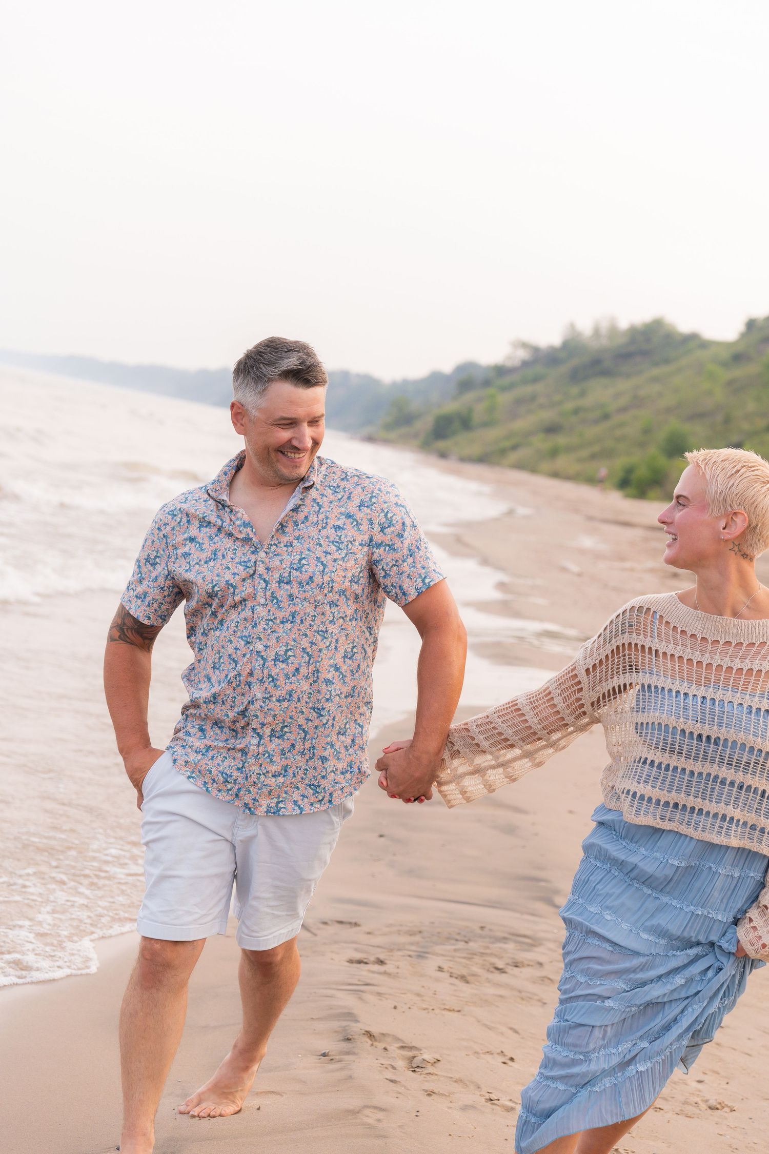 A couple walks hand-in-hand on a beach, enjoying the scenic view.