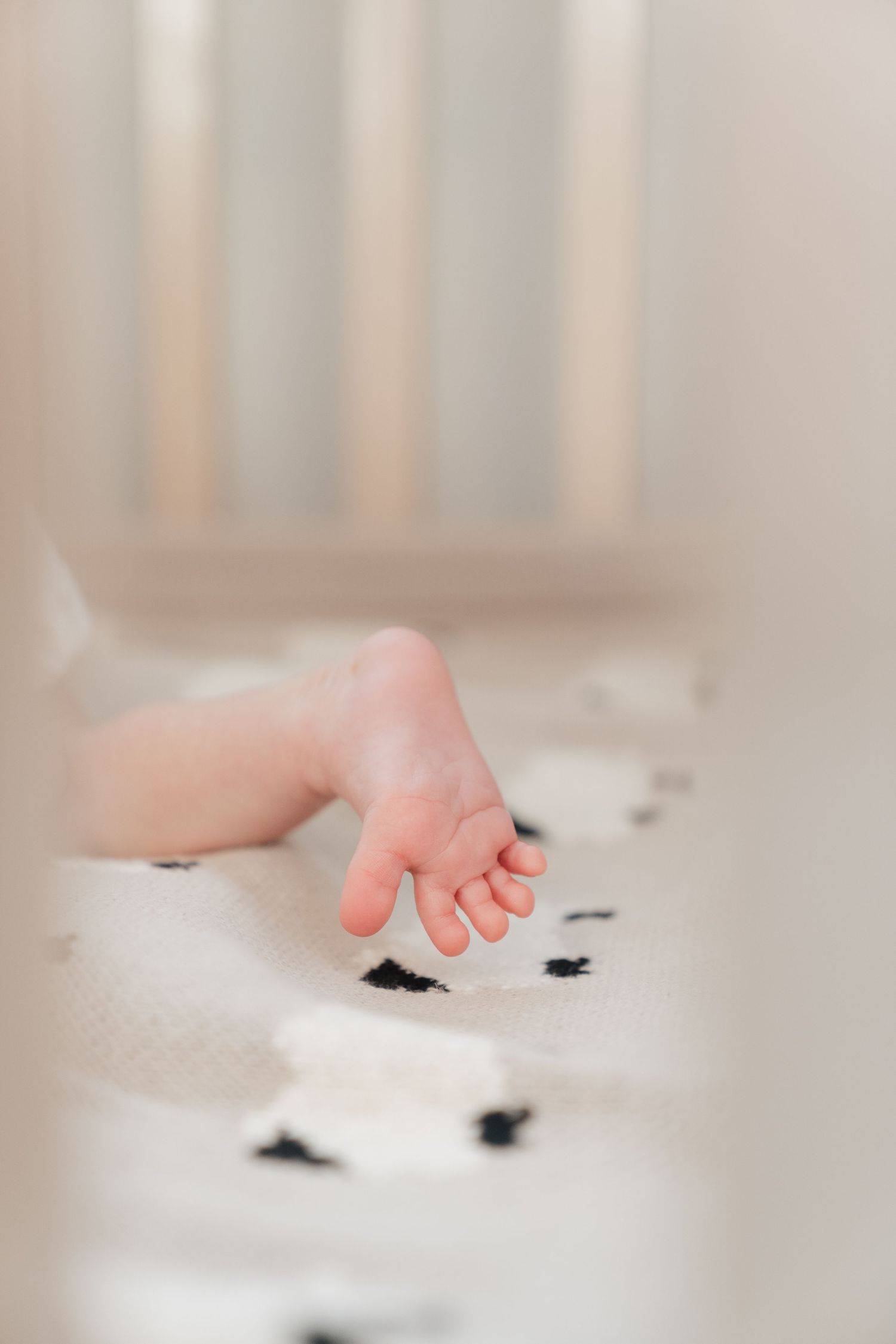 A close-up view of a person's bare feet resting on a patterned blanket or sheet.
