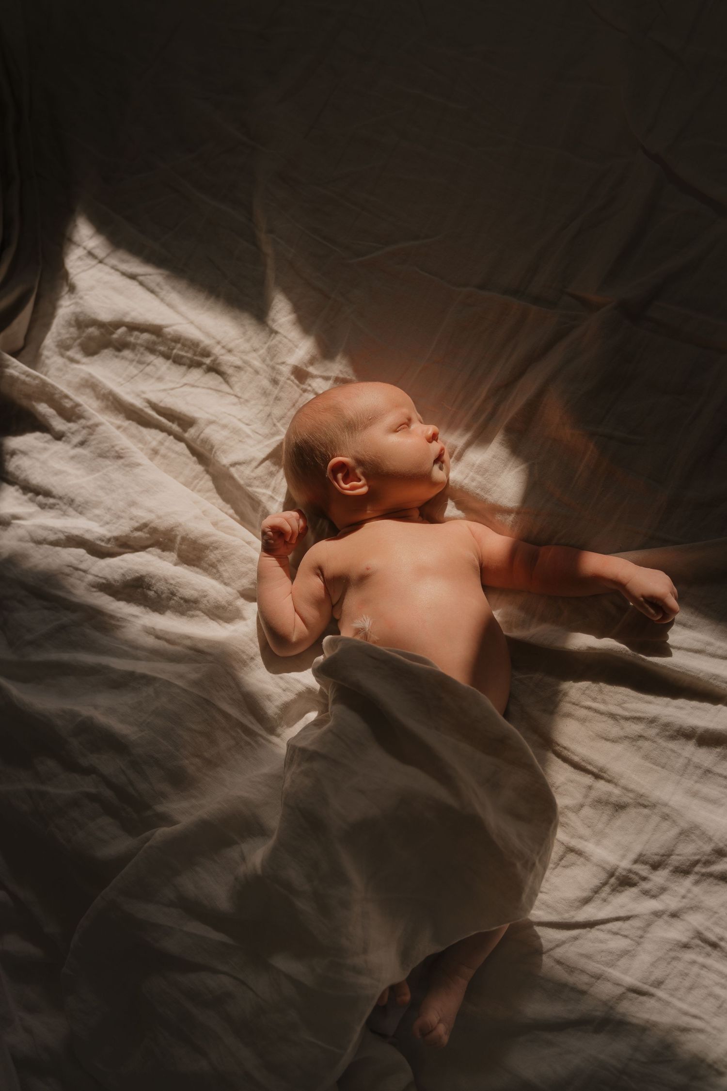 A sleeping newborn baby is wrapped in a soft blanket, lying peacefully on a bed.