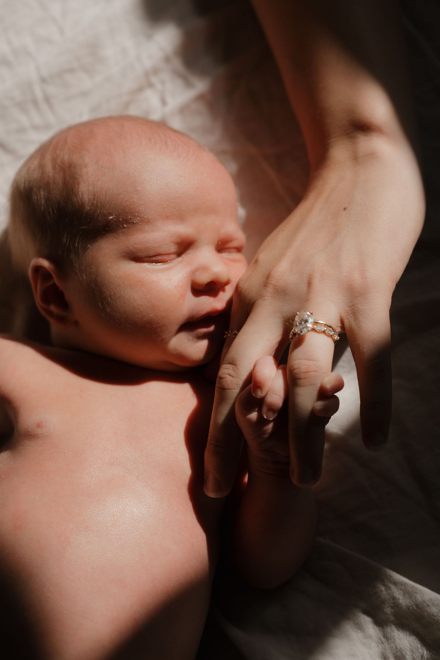 A newborn baby sleeping peacefully, with a hand gently resting on their face.