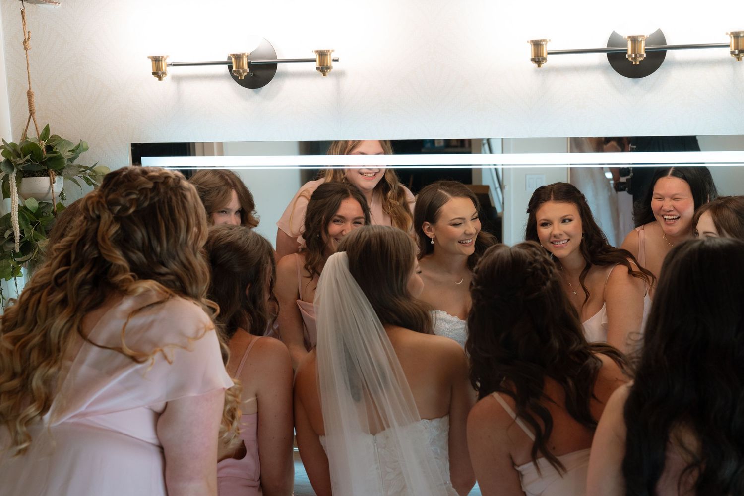 A group of women, some wearing wedding dresses, standing together and smiling at the camera.