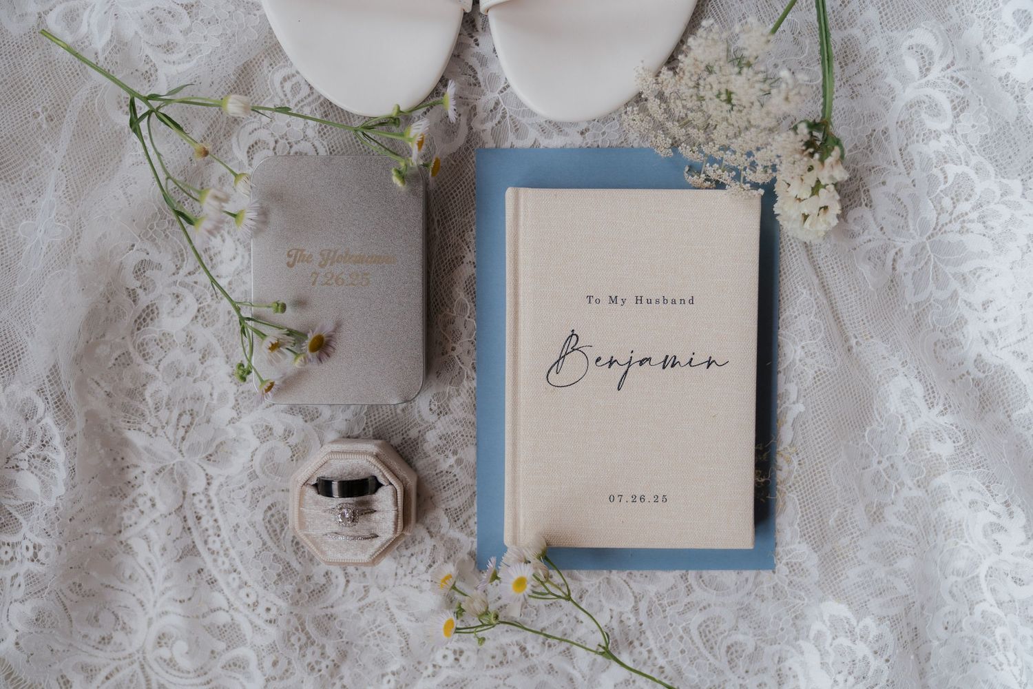 An open book titled 'Inspiration' sits on a lace cloth, surrounded by small white flowers and a glass jar.